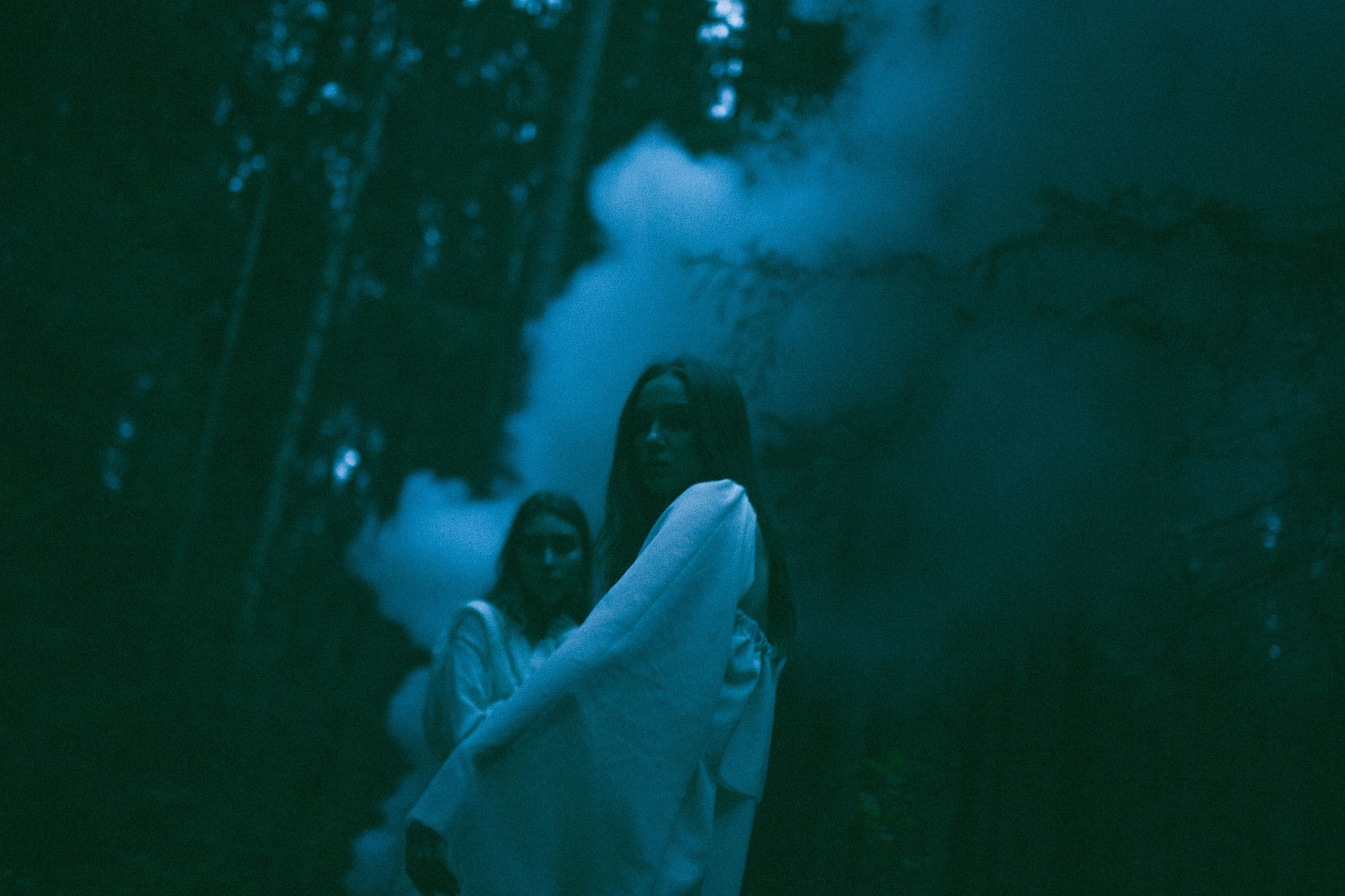 Две девушки в светлых платьях в лесу на фоне дыма