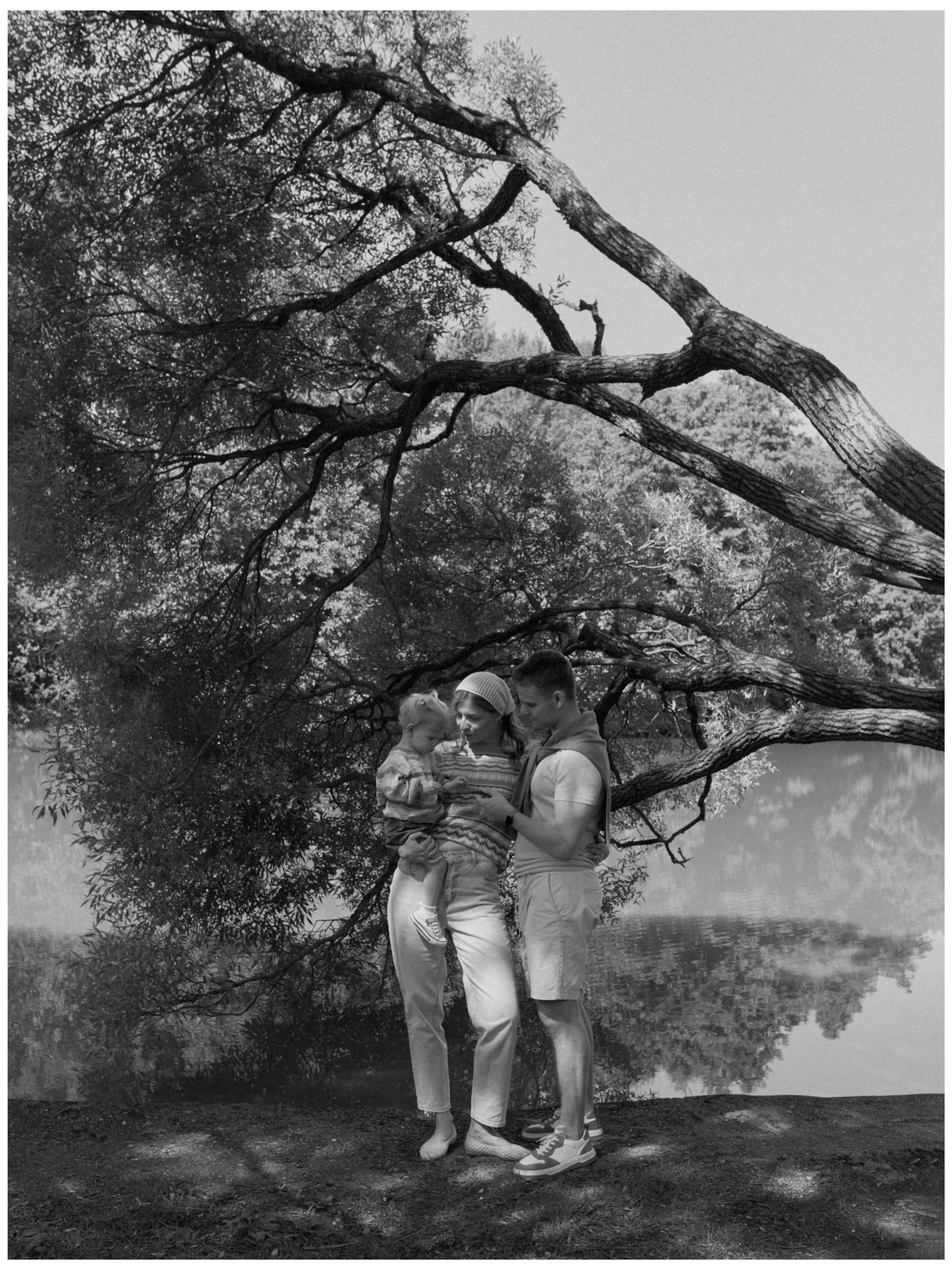 Чёрно-белый семейный портрет родителей с ребёнком под деревом