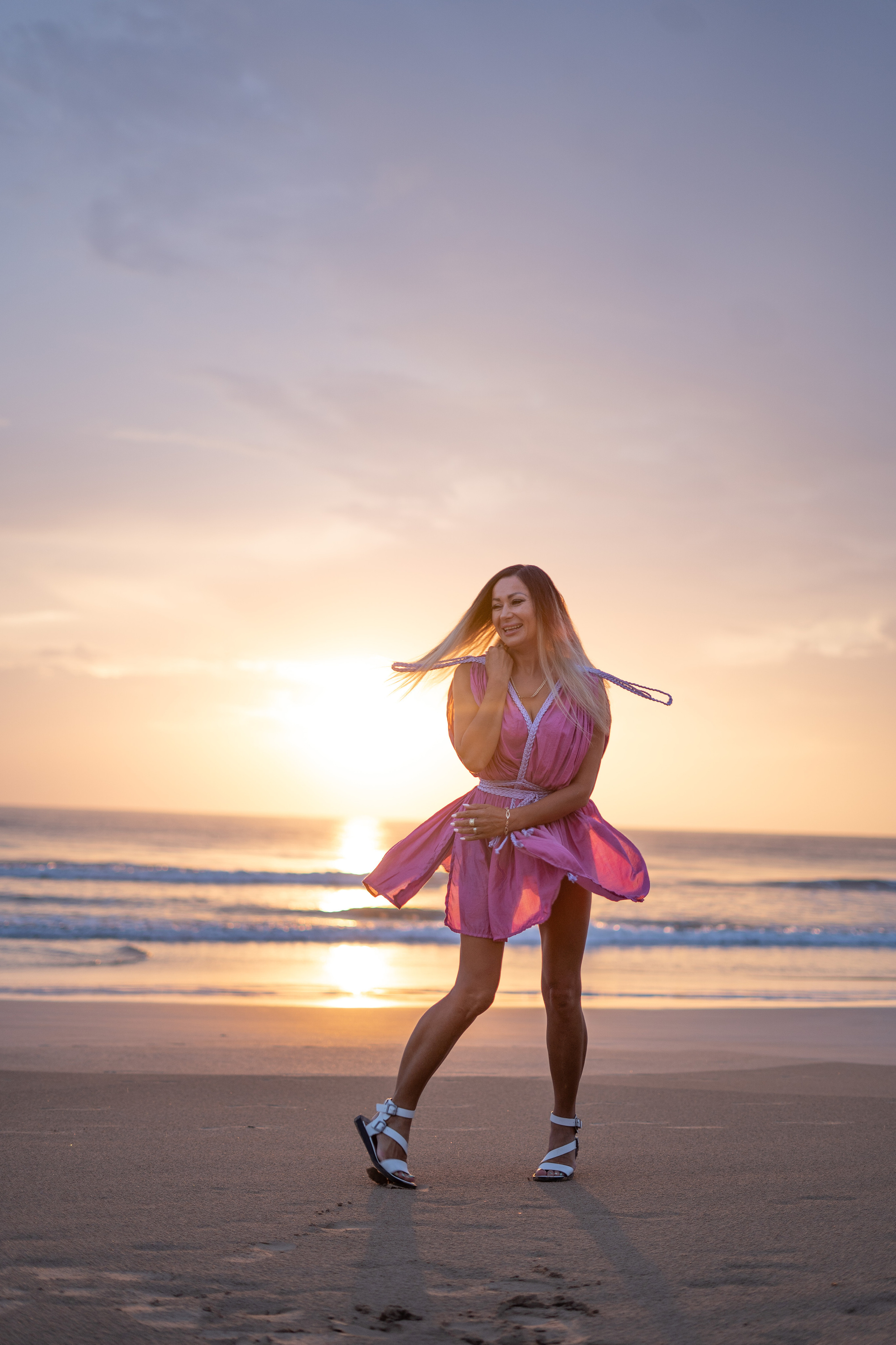 a girl standing at the water's edge at sunset