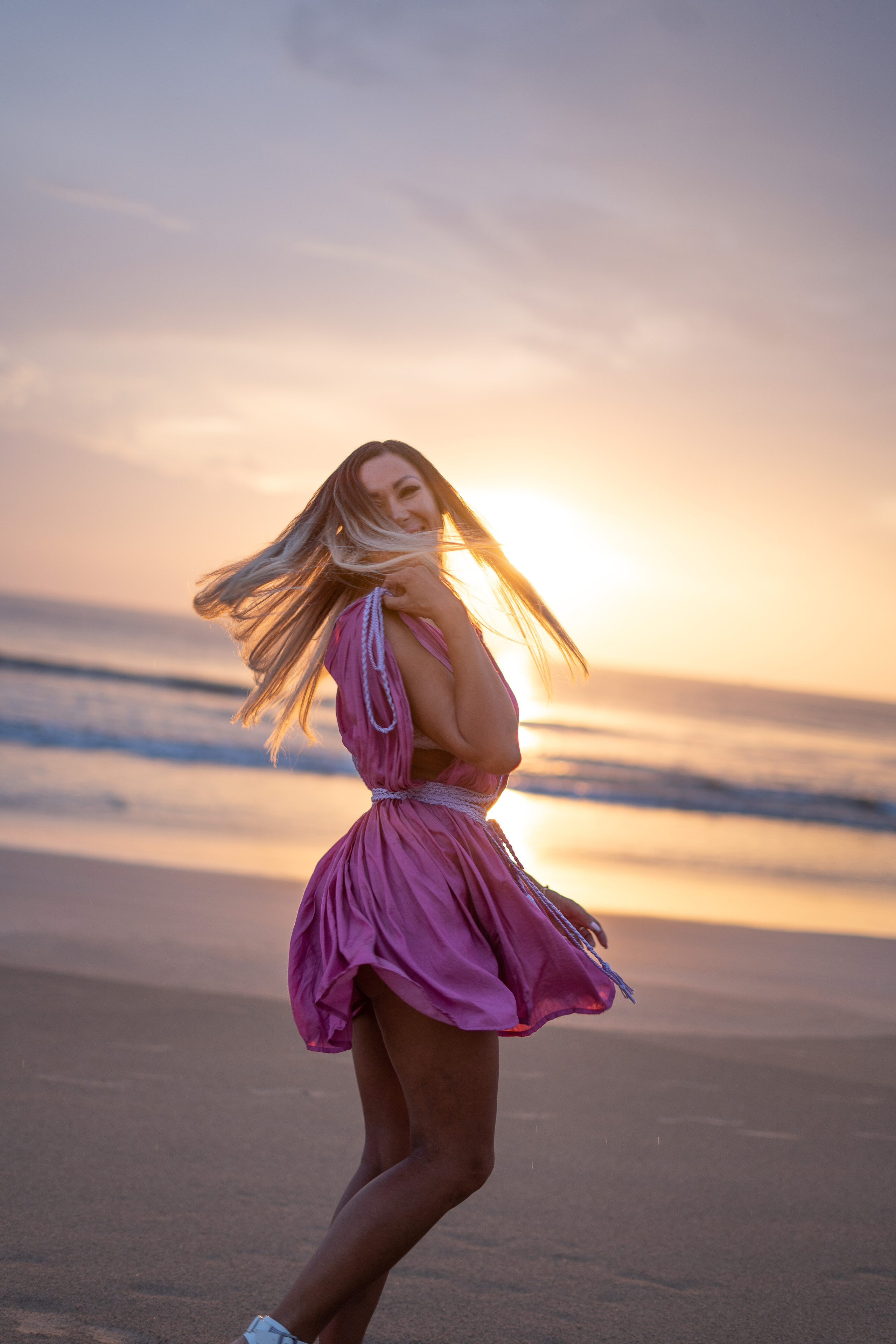a beautiful girl posing on the shore of the ocean at sunset