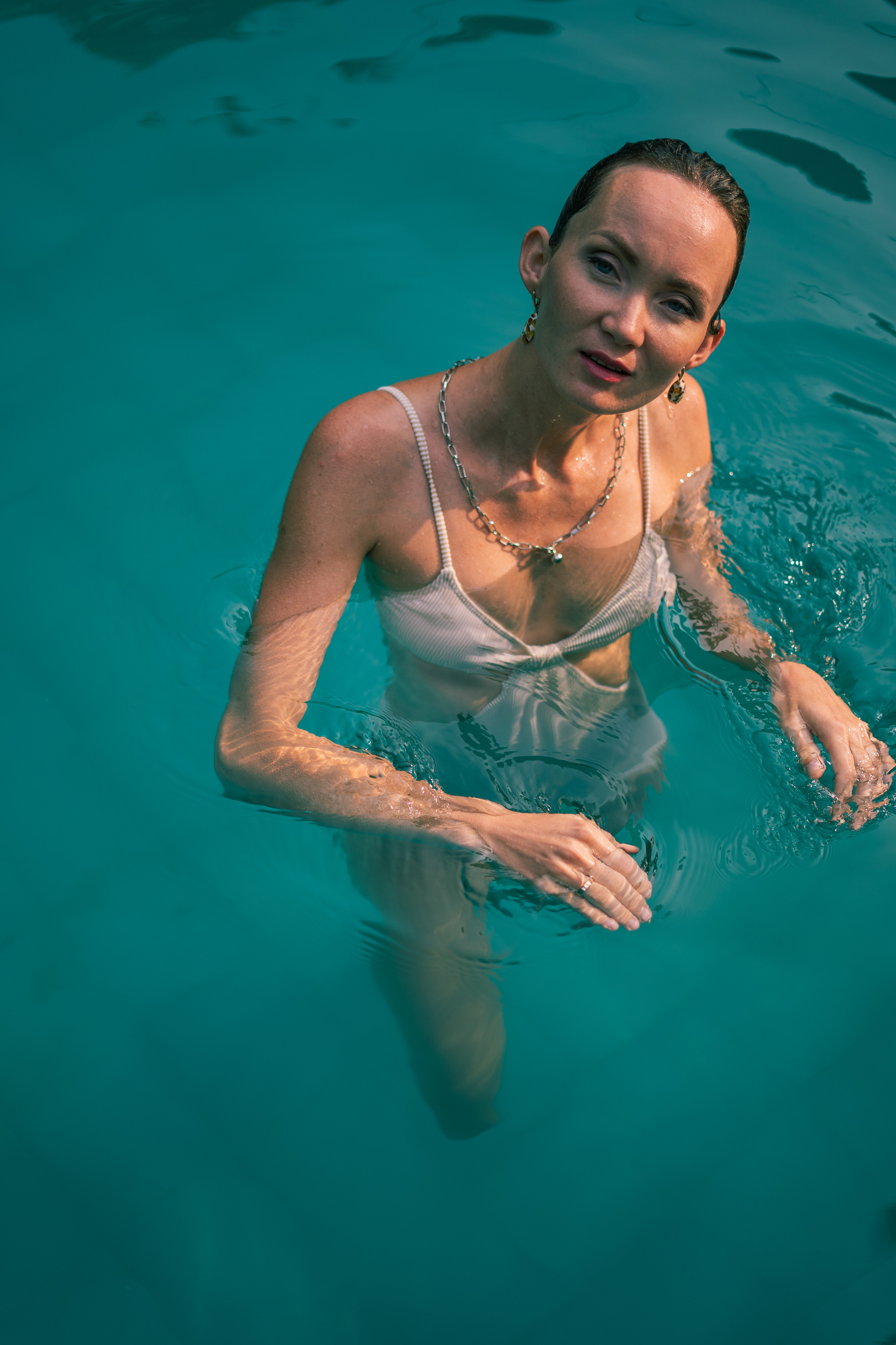 a girl in a white swimsuit taking a selfie in the pool