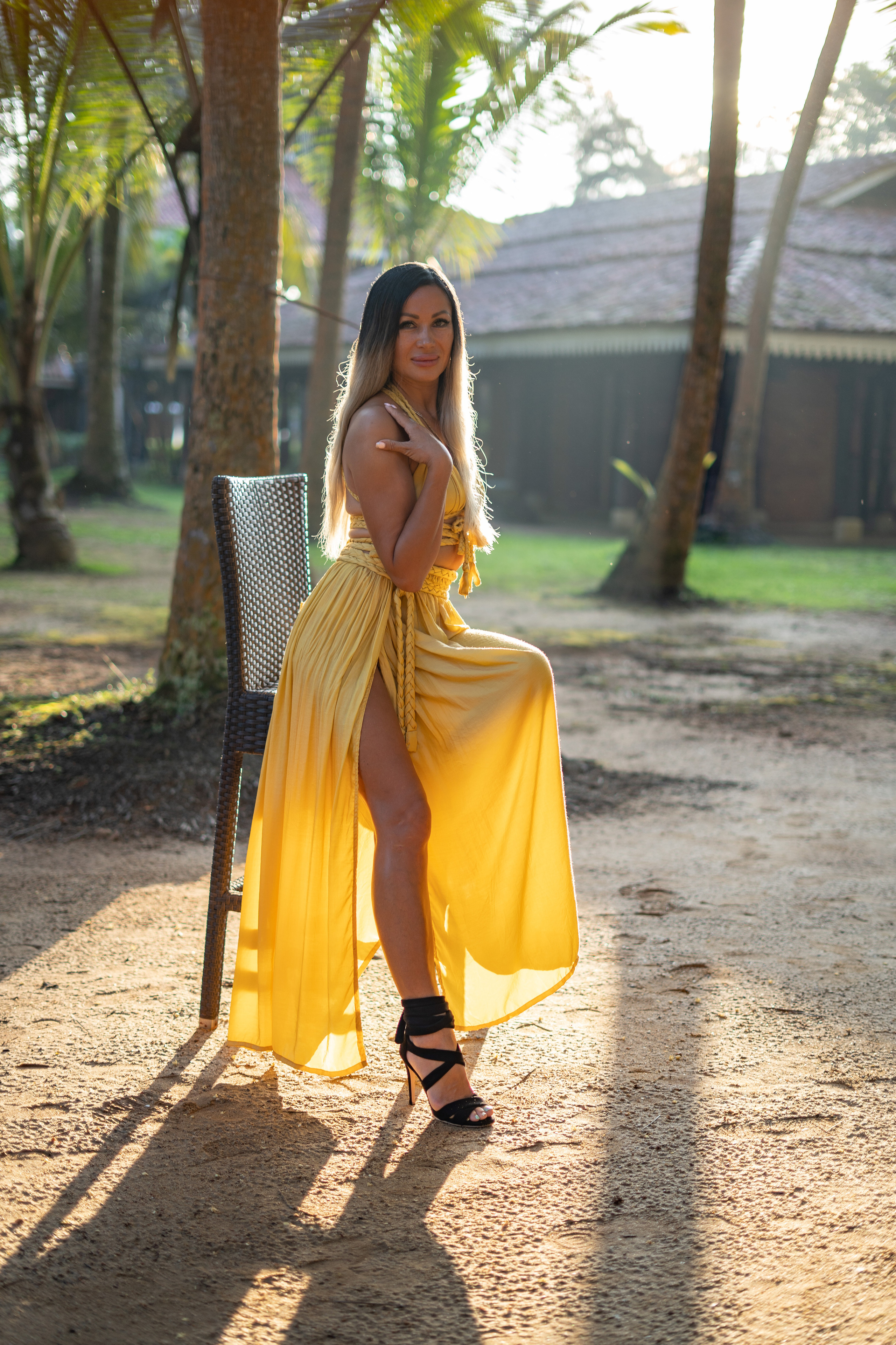 a girl in a yellow dress at a villa surrounded by palm trees