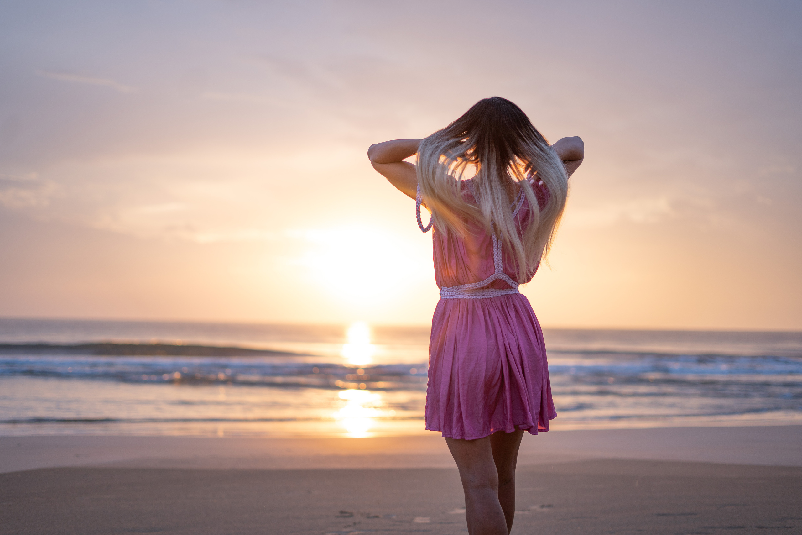 a beautiful girl with flowing hair against the sunset by the ocean
