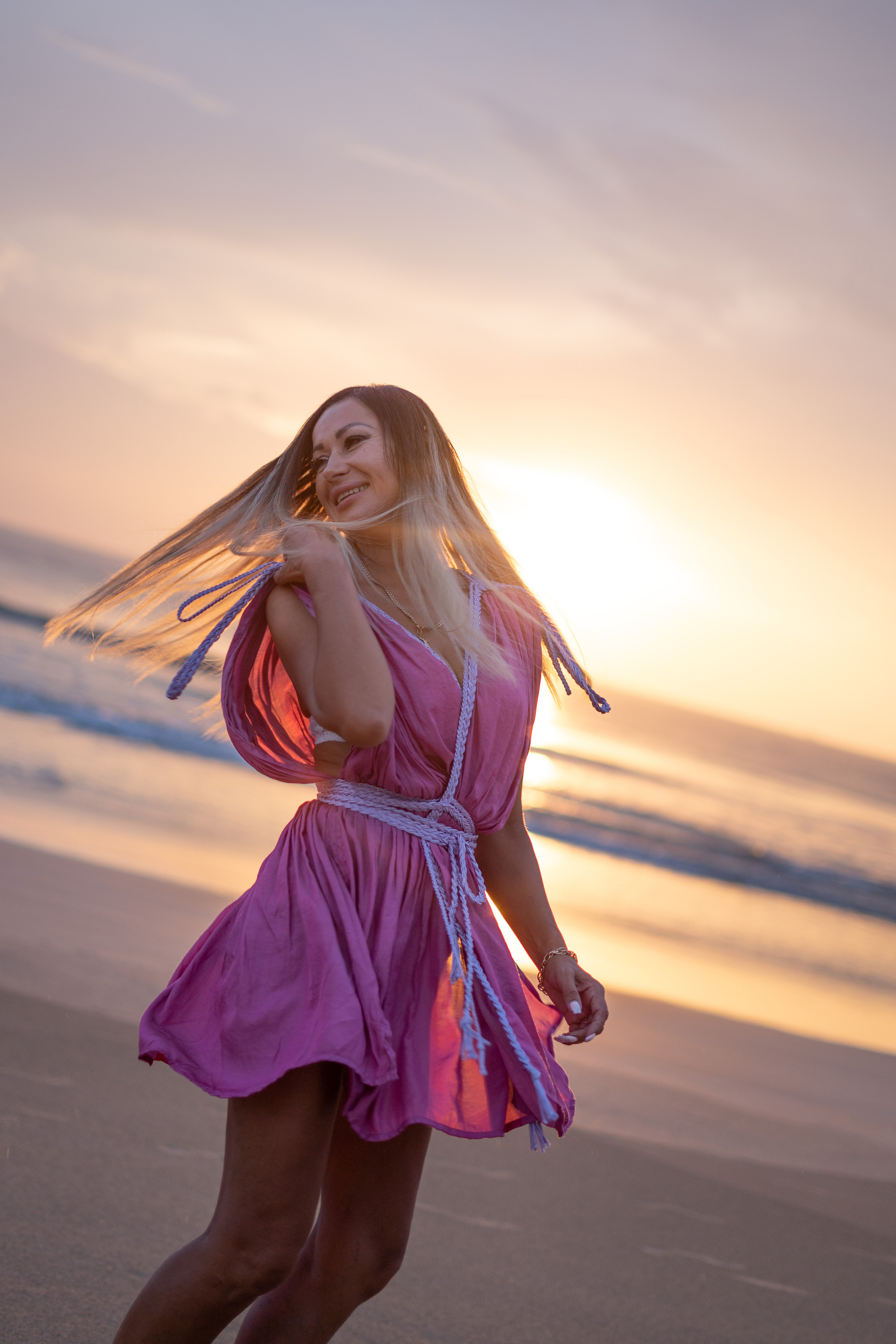a girl with the sunset in the background by the ocean