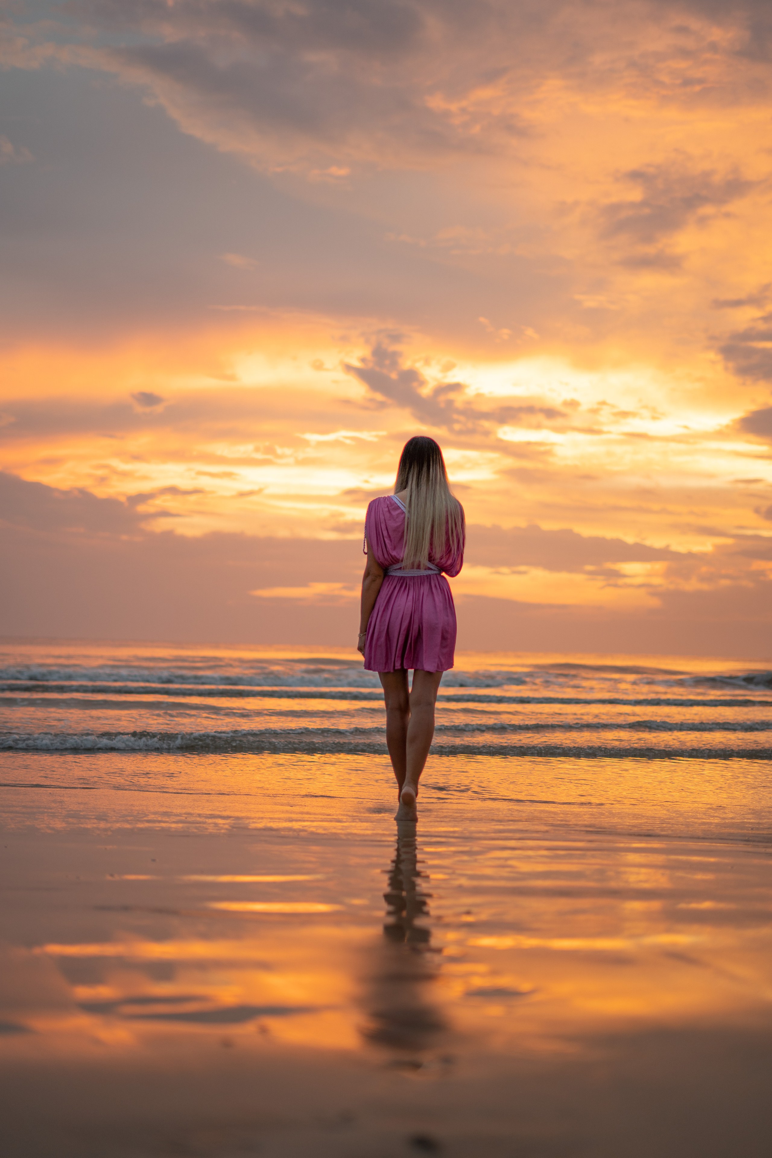a girl with the colorful sunset over the ocean in the background