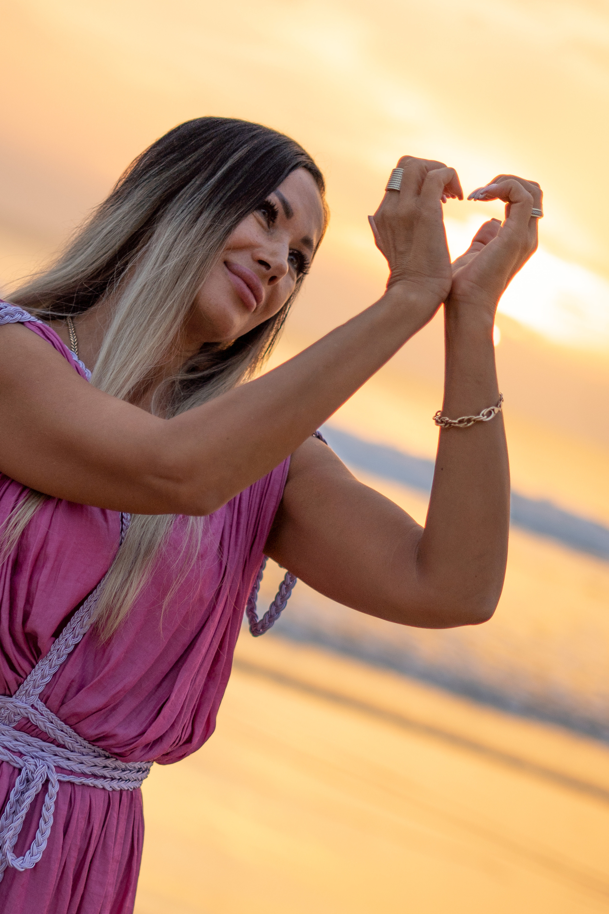 a beautiful girl smiling with the sunset by the ocean