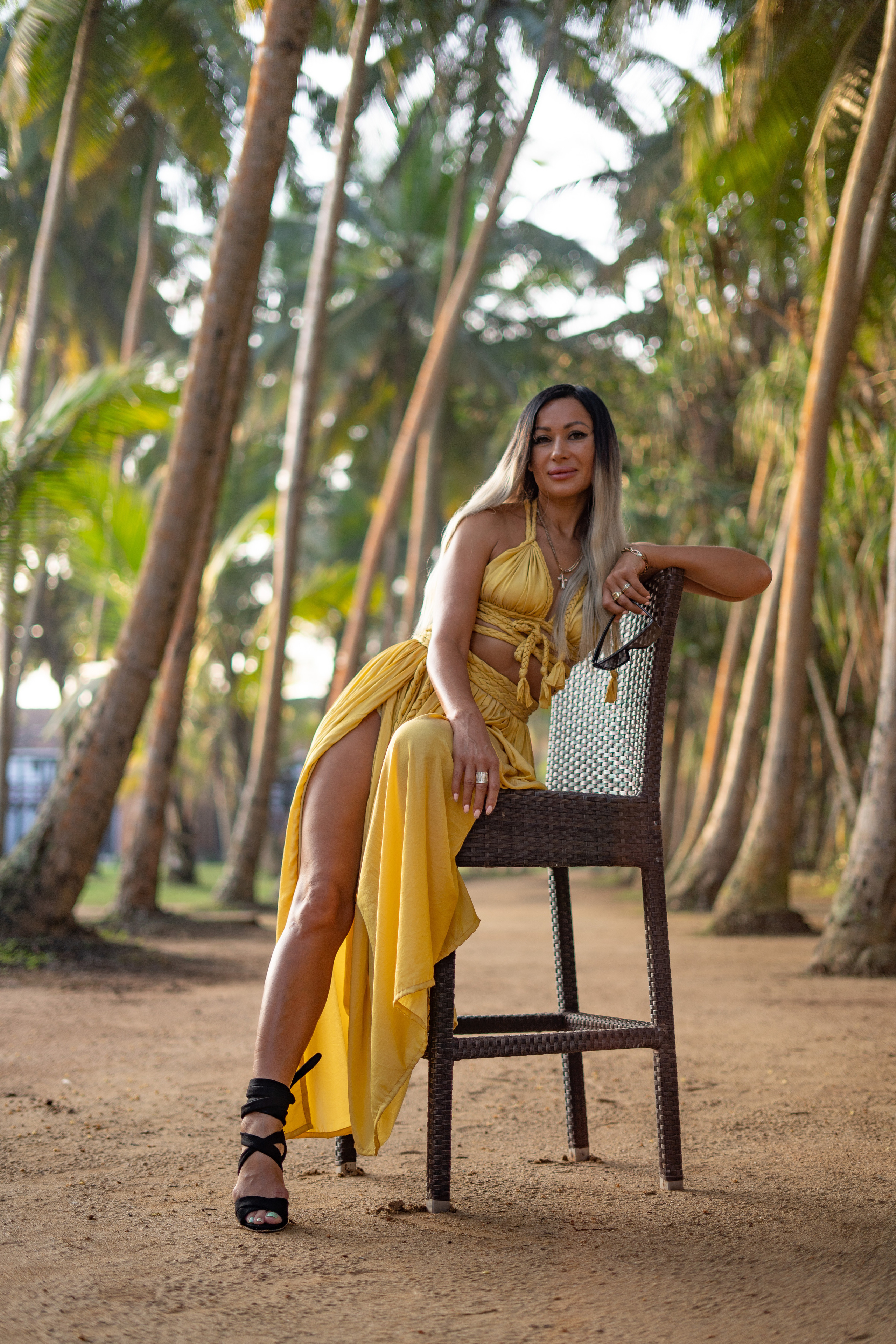 photoshoot of a girl in a long yellow dress at a villa with palm trees