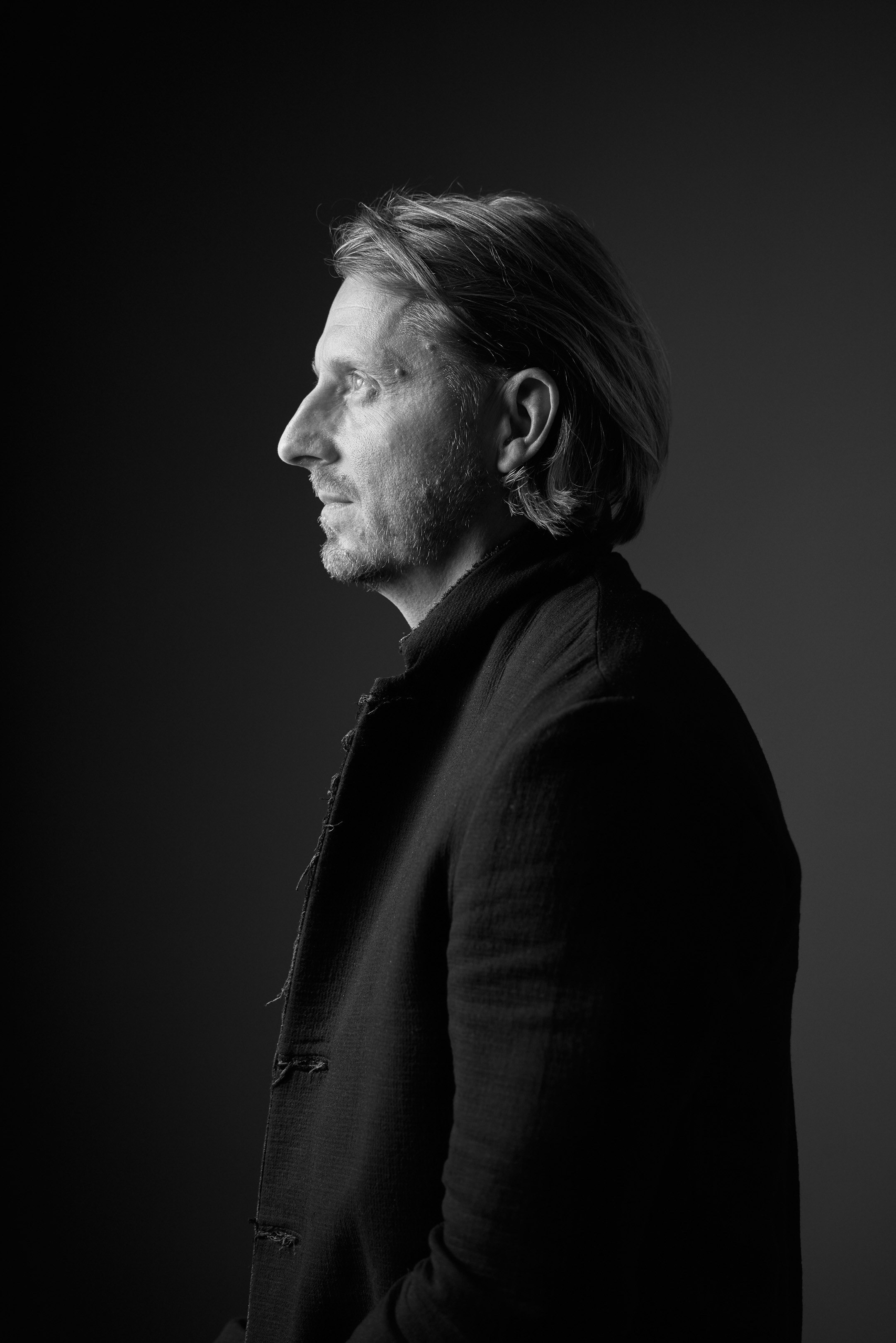 Black and white business portrait of a confident man in a suit on a black background