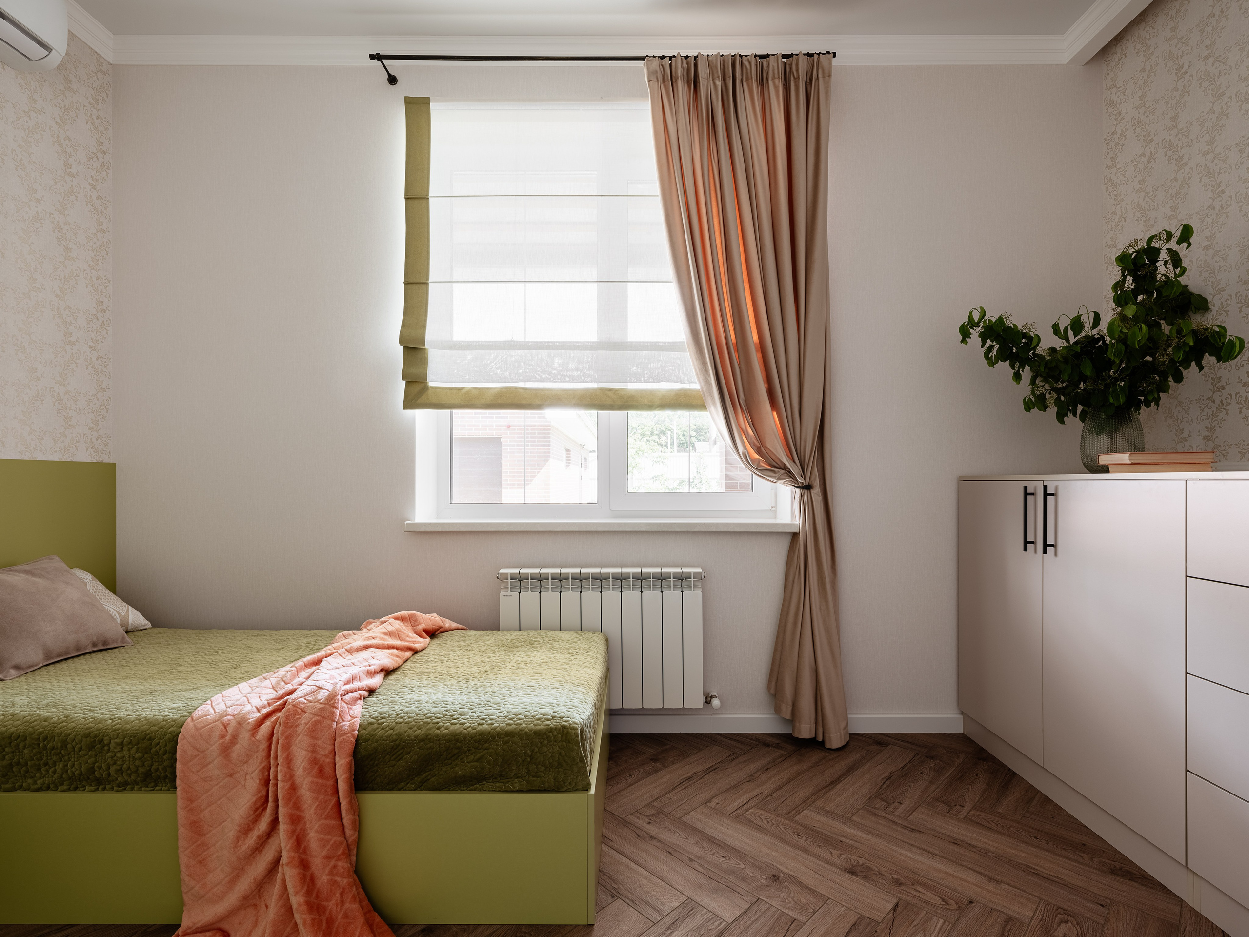 Интерьер спальни с зелёным покрывалом и мягкими подушками, бежевые и оливковые шторы на окне, светлая мебель с акцентами под дерево, уютный современный стиль, дизайнер Алина Чередниченко, фотограф Сергей Денисенко