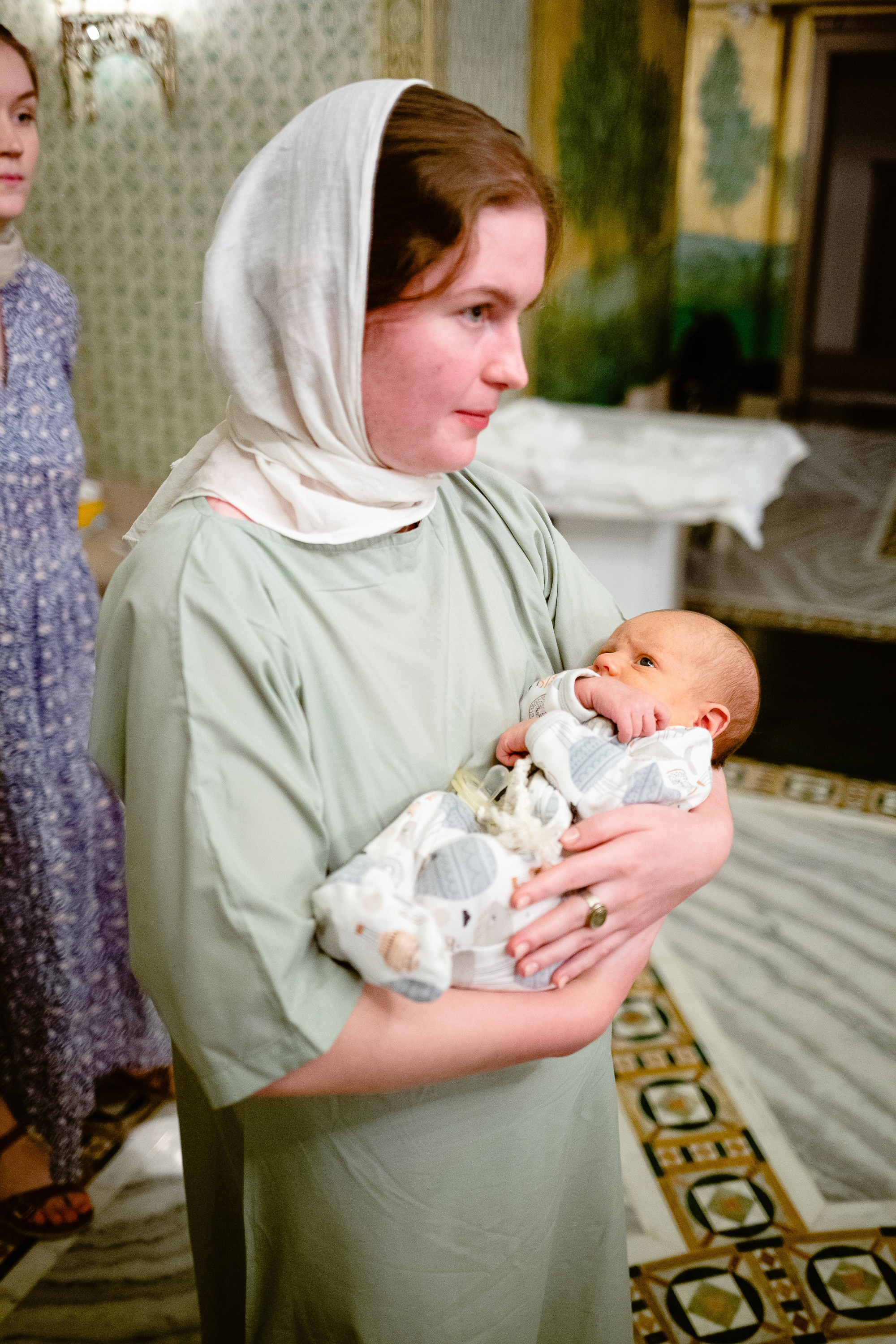 Фотосъемка крещения в сретенском монастыре. Крестная держит на руках младенца.