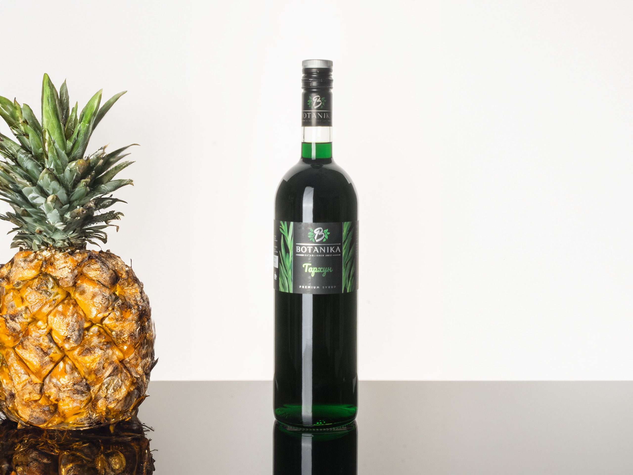 бутылка с сиропом на стекле и рядом ананас
