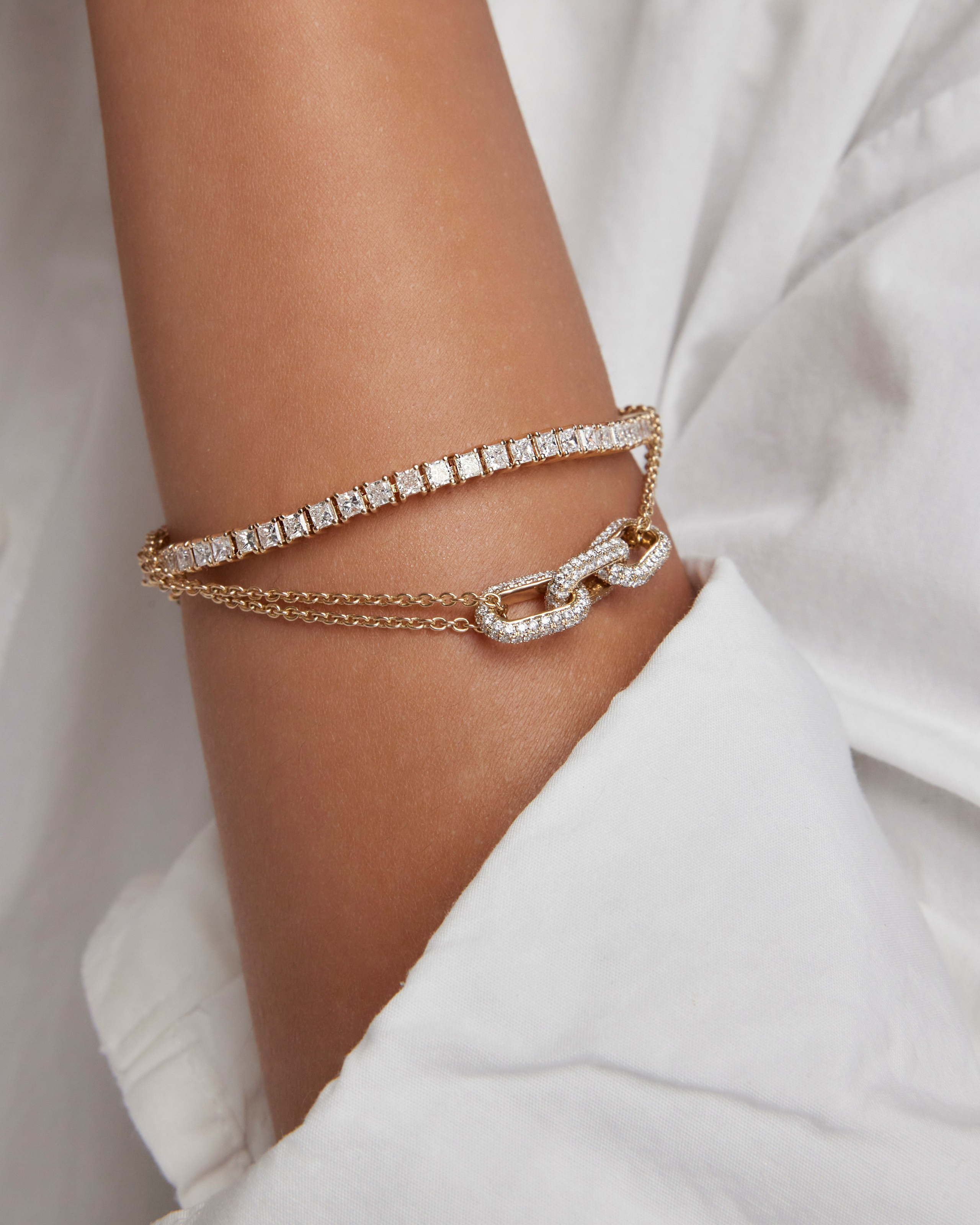 Close-up of layered gold bracelets on a model's wrist, highlighting timeless elegance.