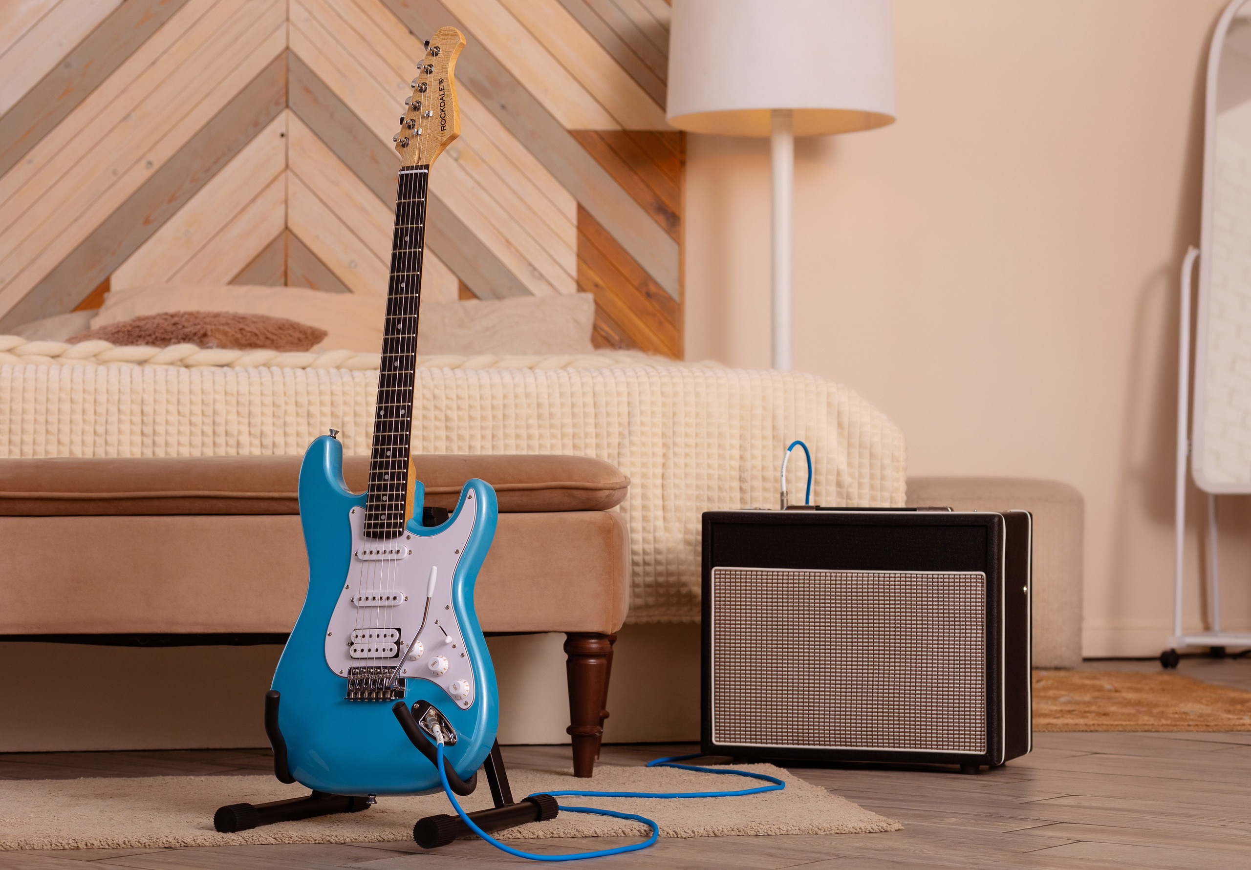 На подставке стоит голубая акустическая гитара, перед ней микрофон.