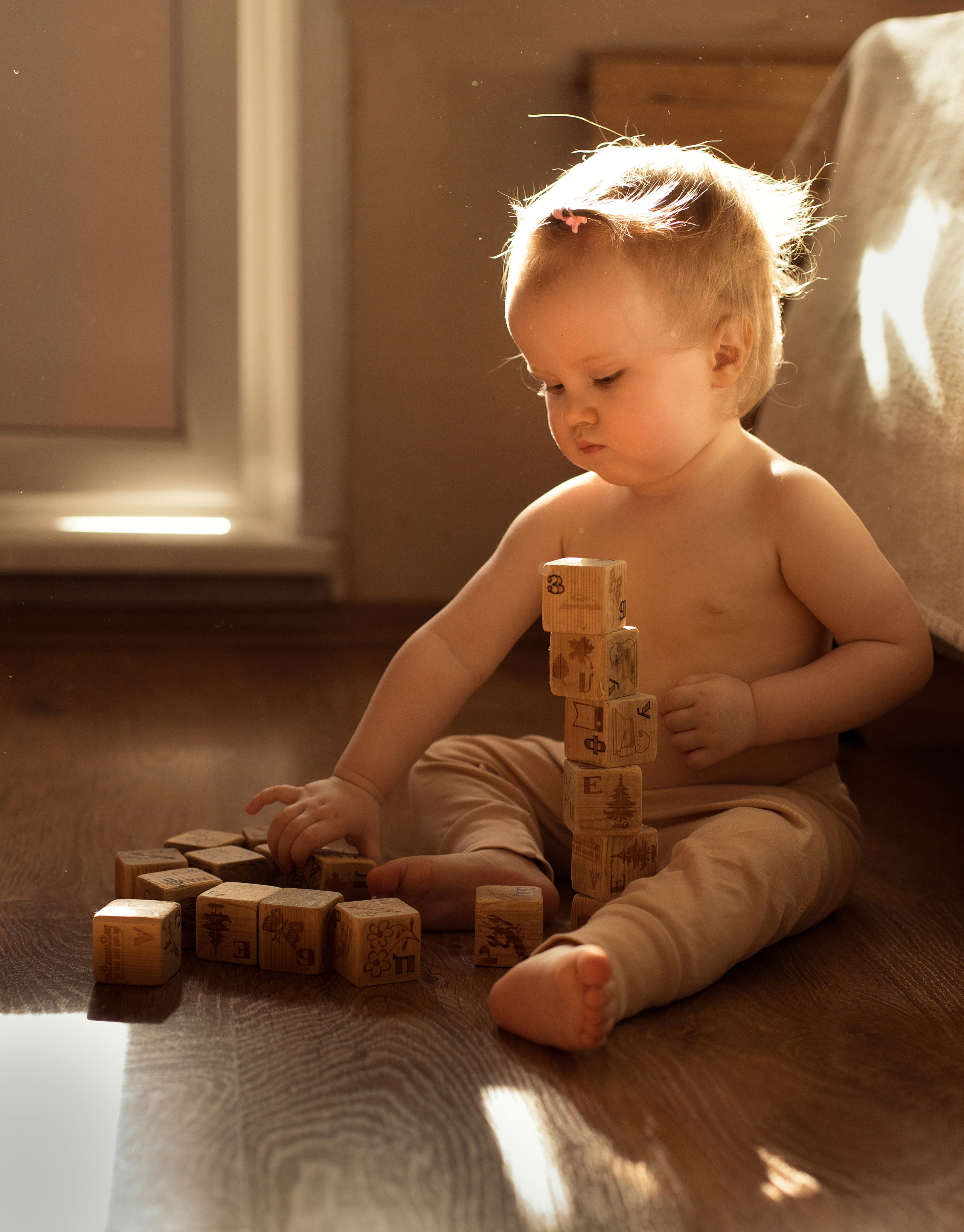 Девочка играет с деревянными кубиками в лучах контрового света