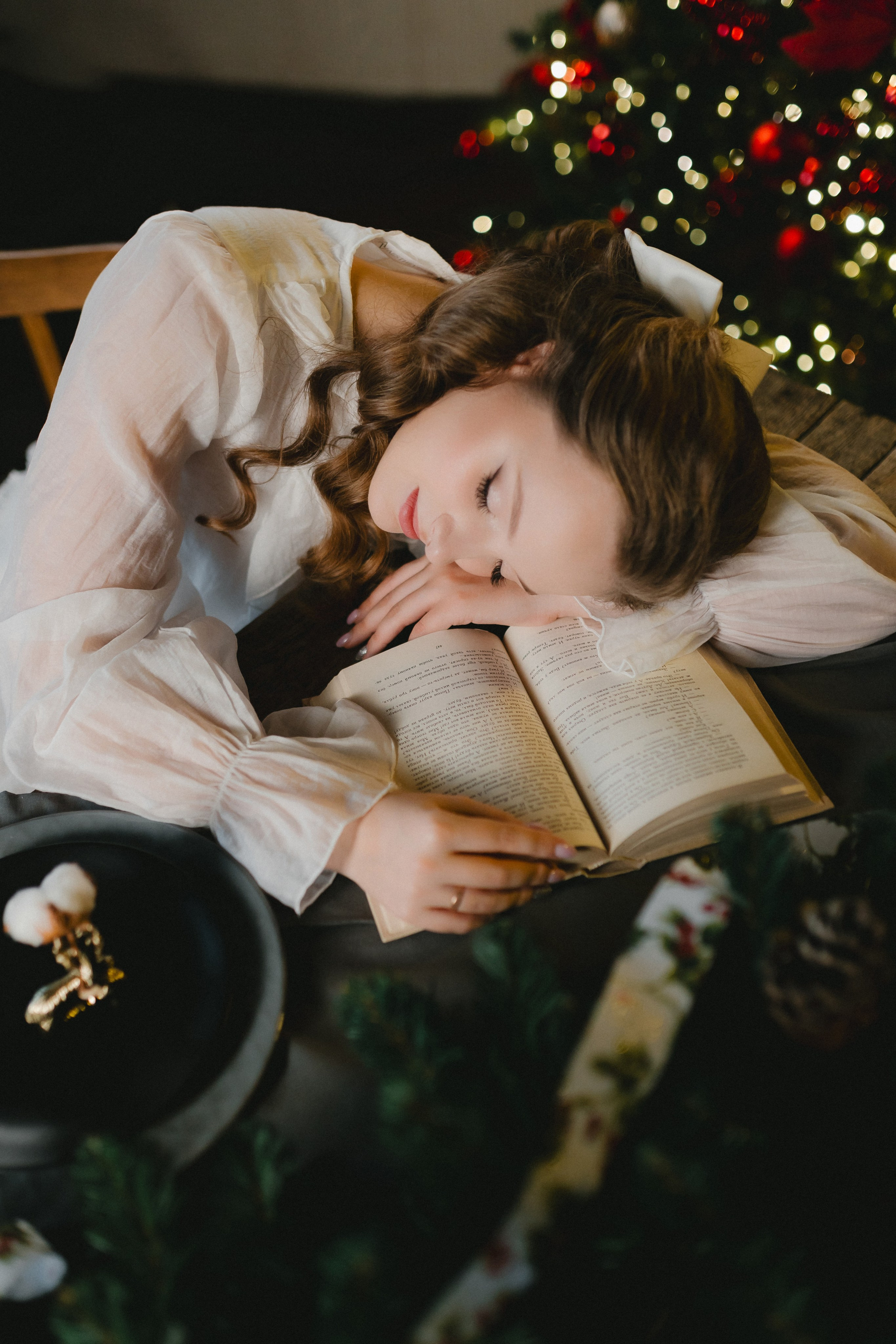 Девушка уснула за чтением книги уютным Рождественским вечером в Мурманске.