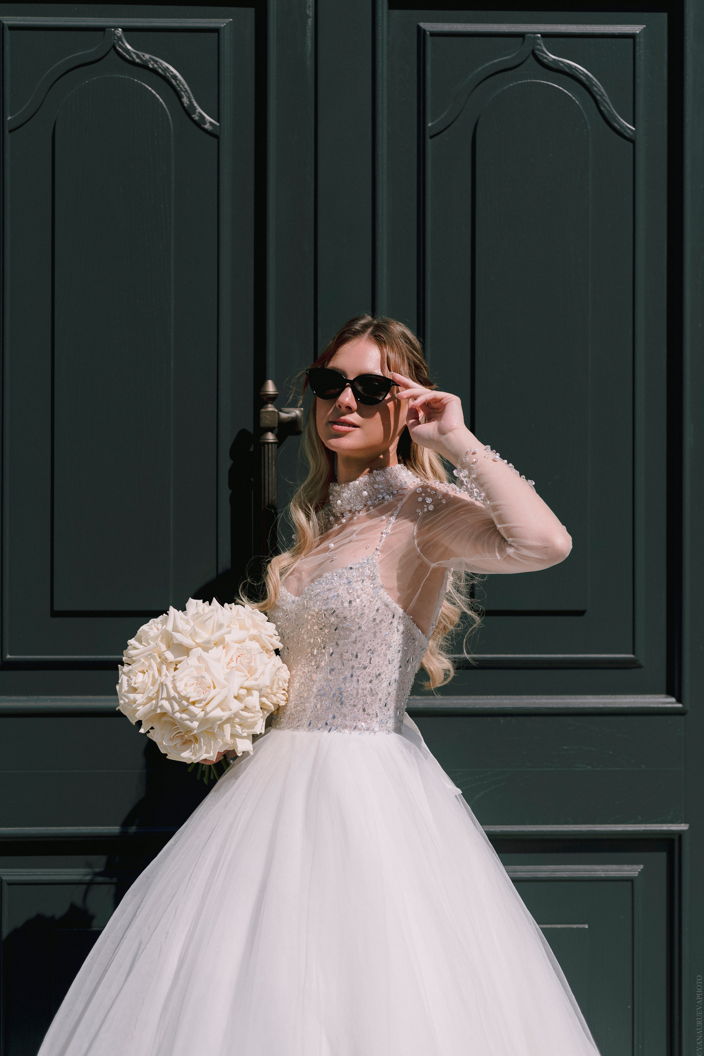 Невеста в солнечных очках на фоне двери