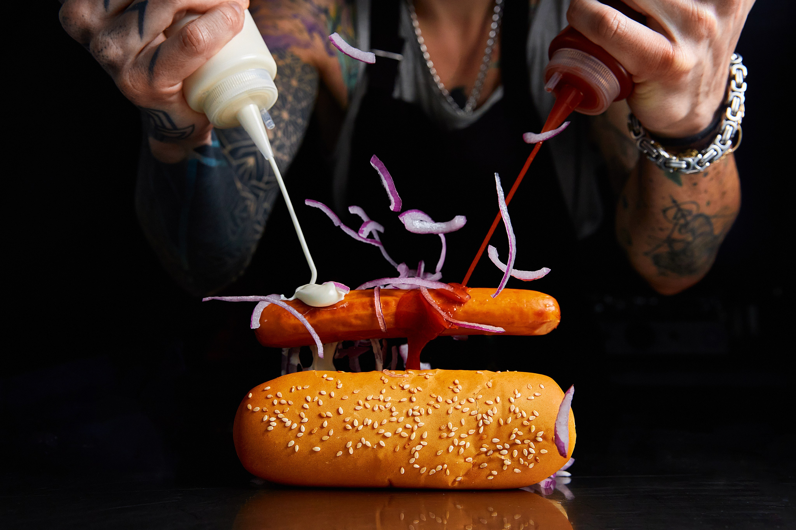 Хот-дог, сосиска, лук и соусы летят на стол