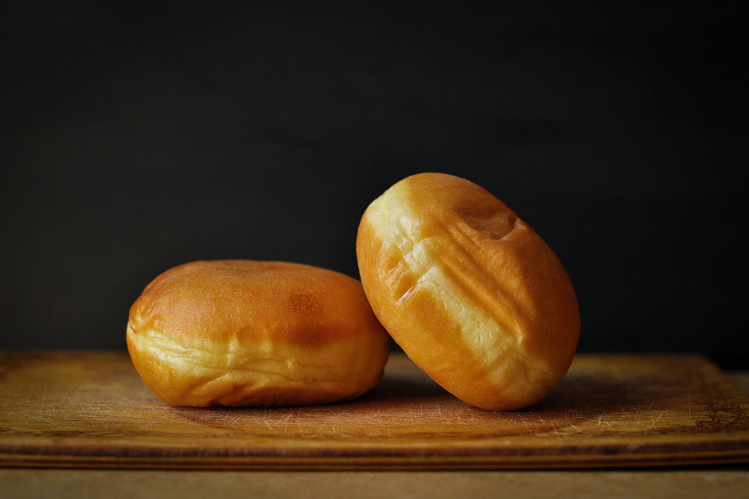 Два пончика на деревянной доске на темном фоне 