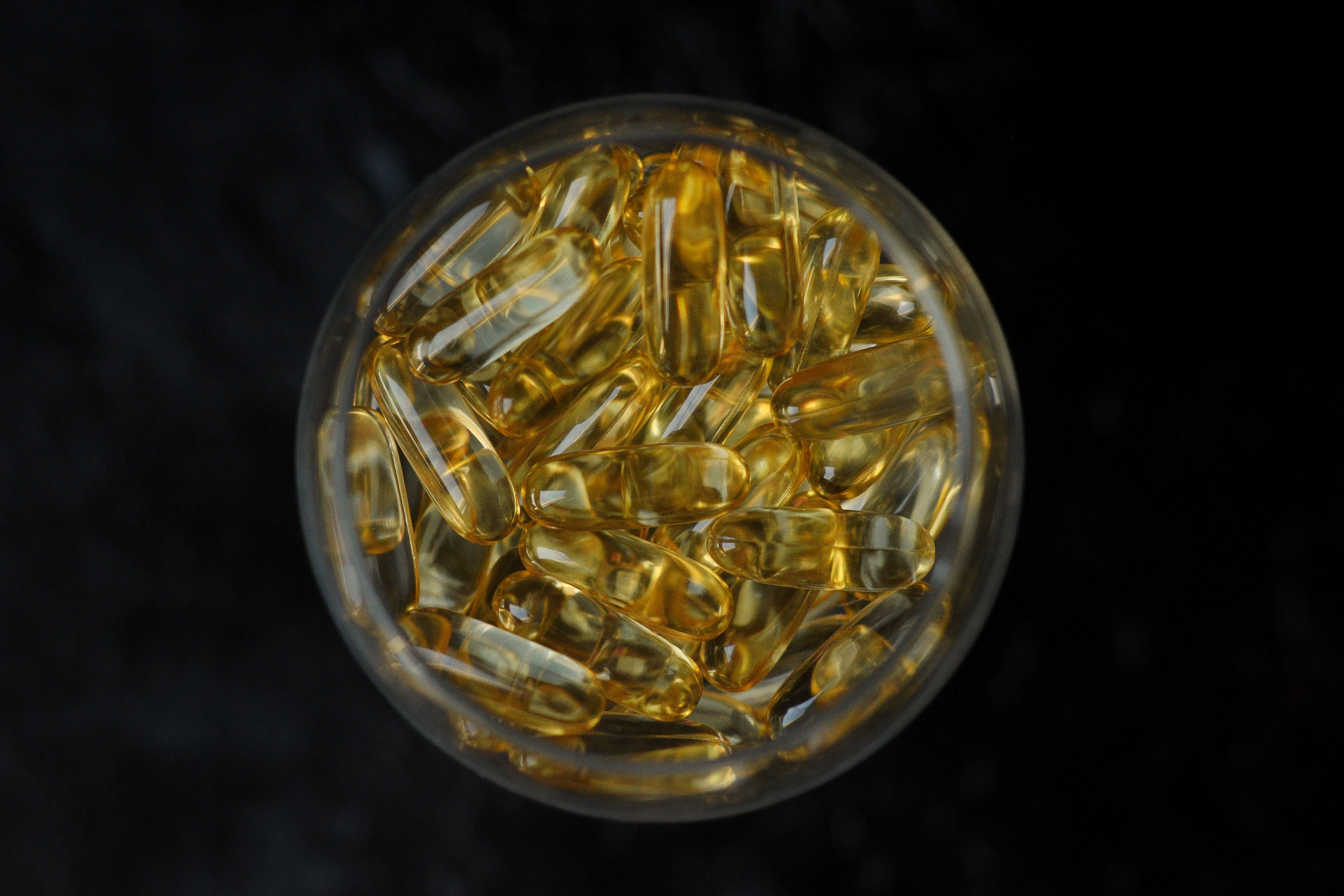 Рыбий жир в прозрачном бокале вид сверху 