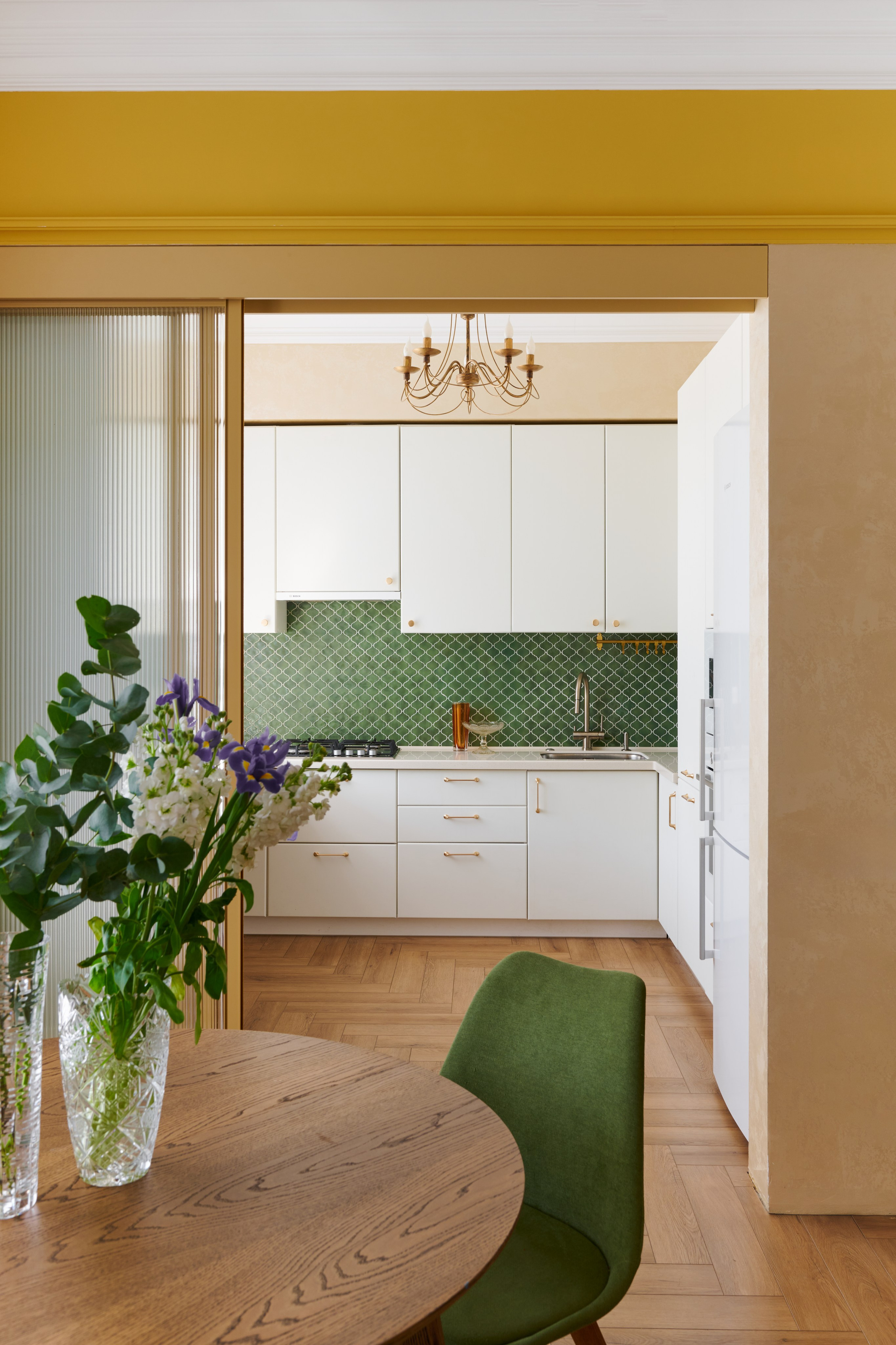 Проём с жёлтой рамой, зелёный стул и букет на столе