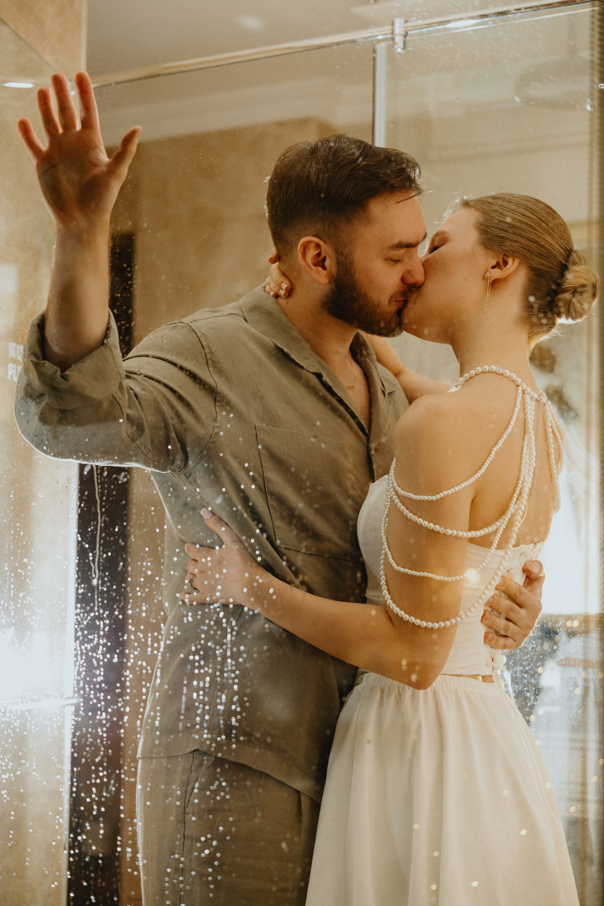 Жених и невеста целуются, их отражение видно в зеркале.