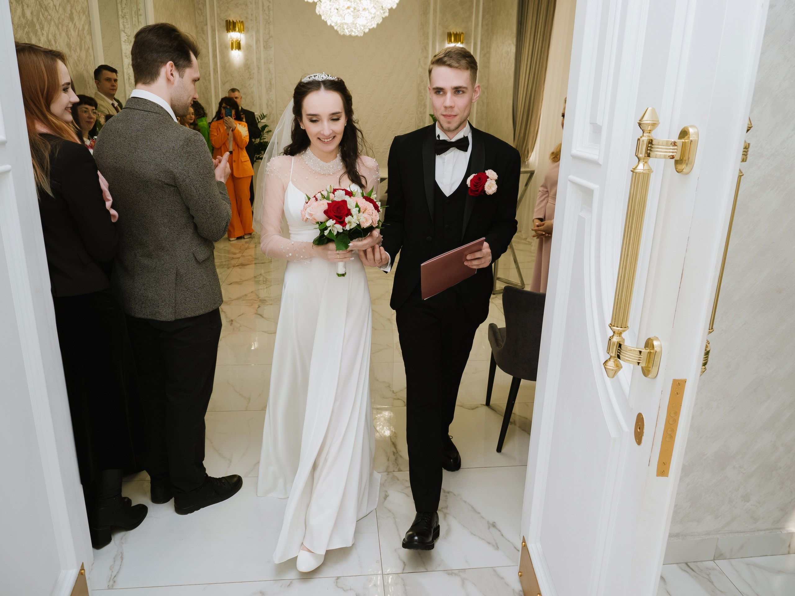 На фото жених и невеста выходят вместе из ЗАГСа после росписи в Москве