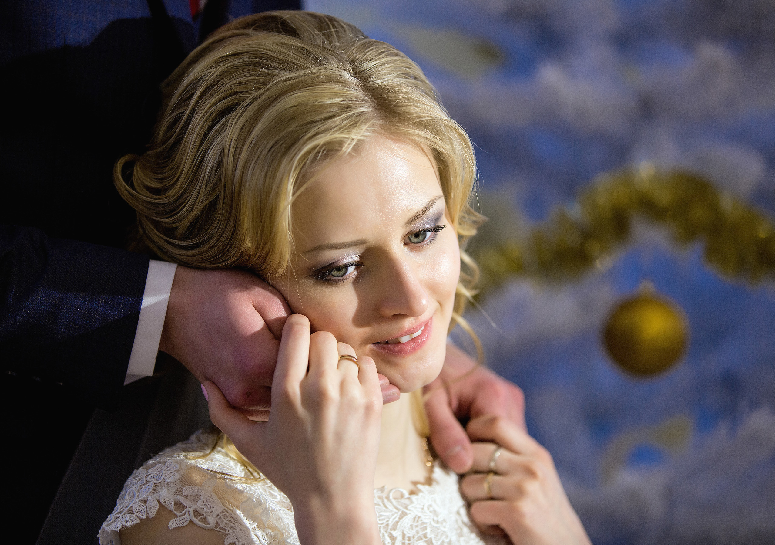 невеста сидит, жених руками нежно обнимает лицо невесты сзади.