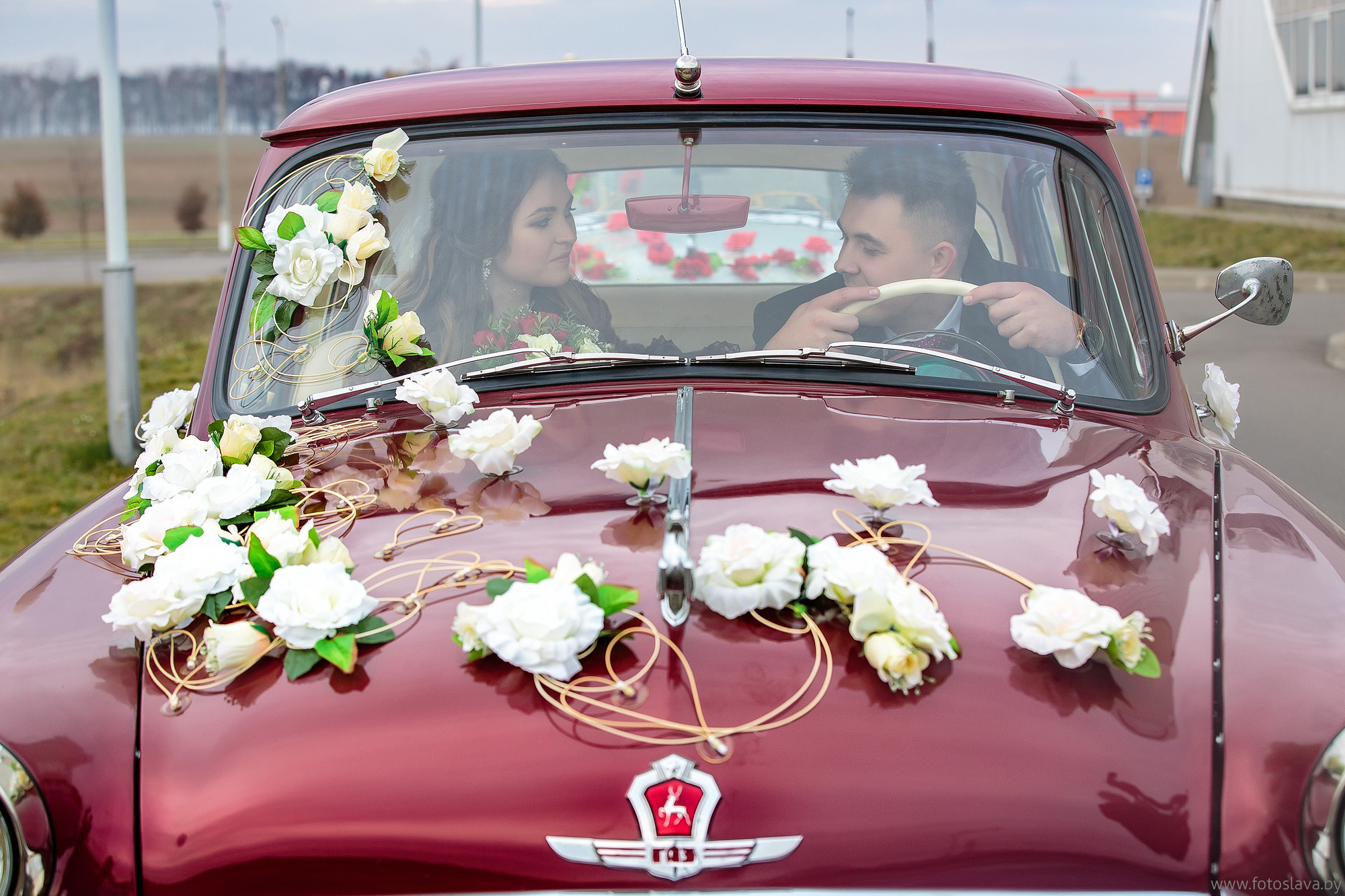 жених за рулем, невеста рядом, снято через стекло ретро авто.