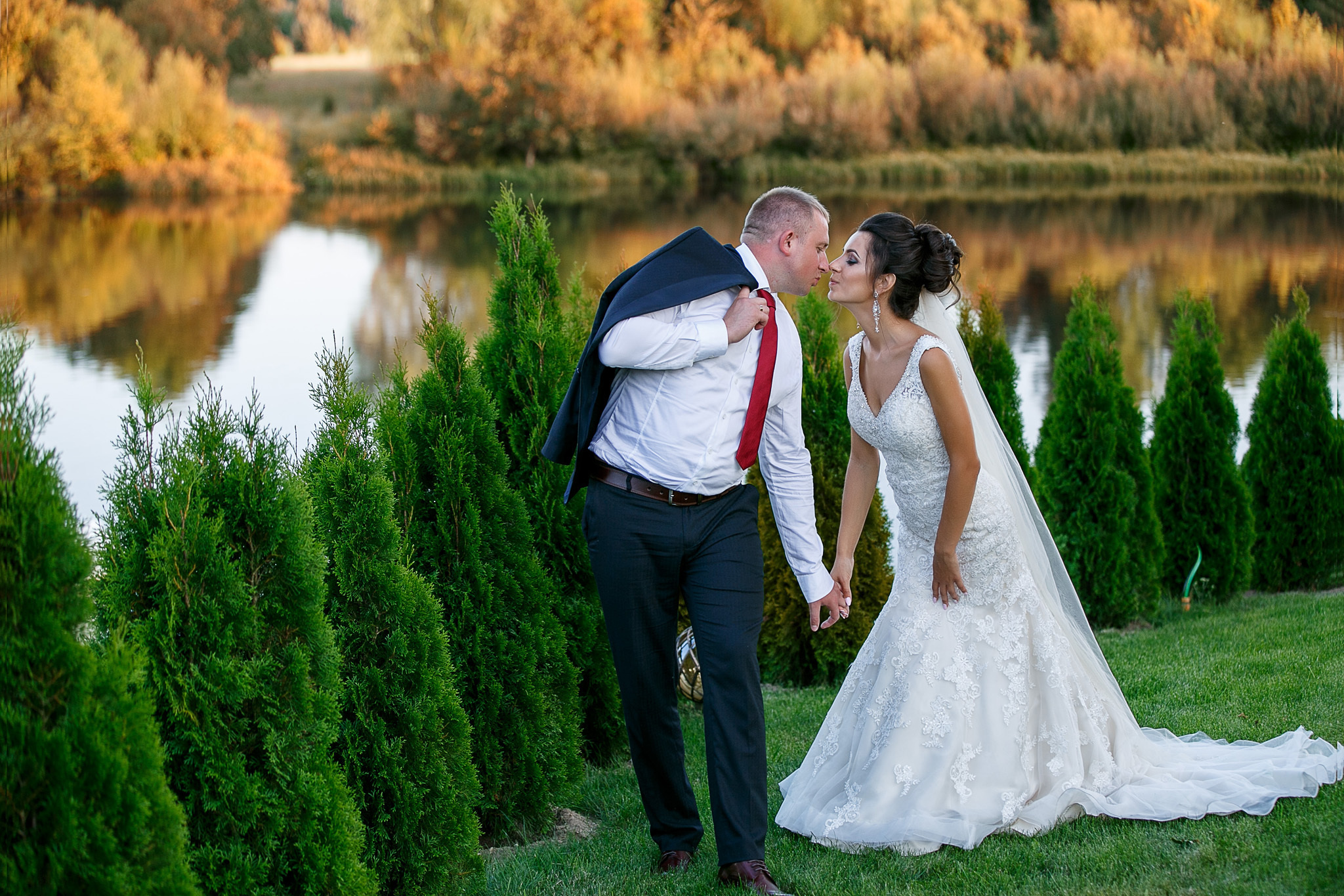 невеста с женихом целуются на фоне озера.