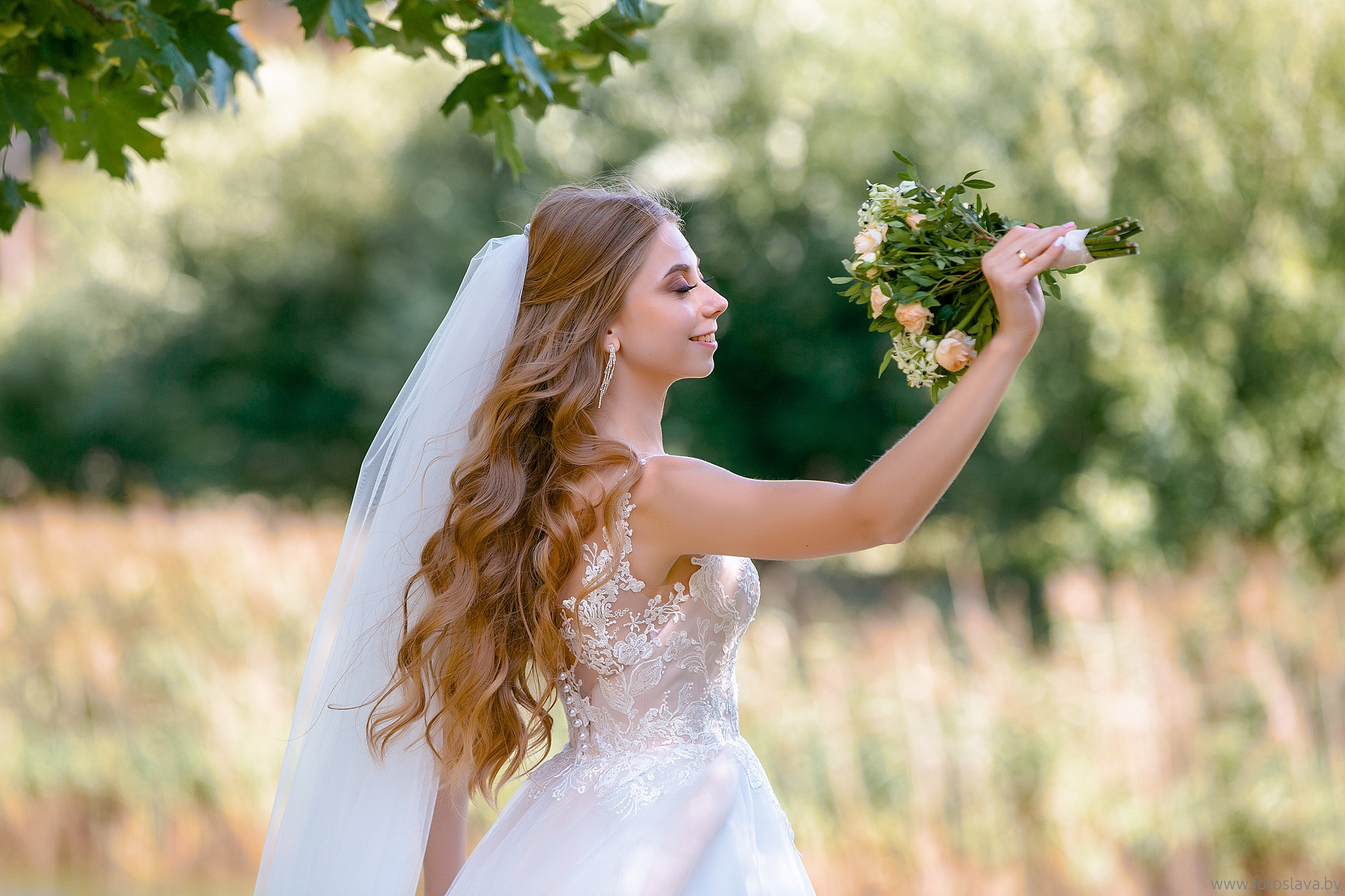 невеста с букетом позирует фотографу.