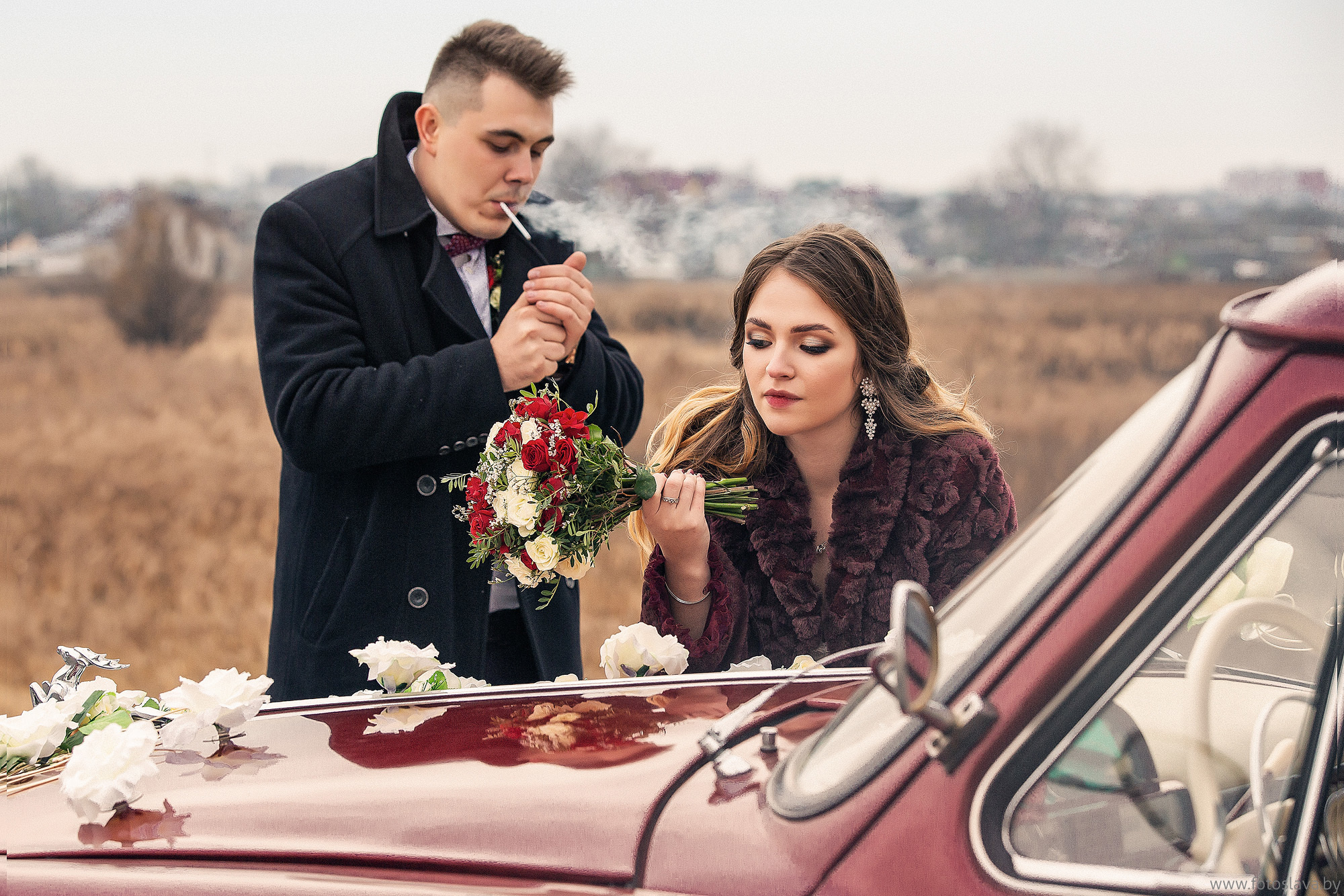жених прикуривает сигарету невеста облокотилась на капот.