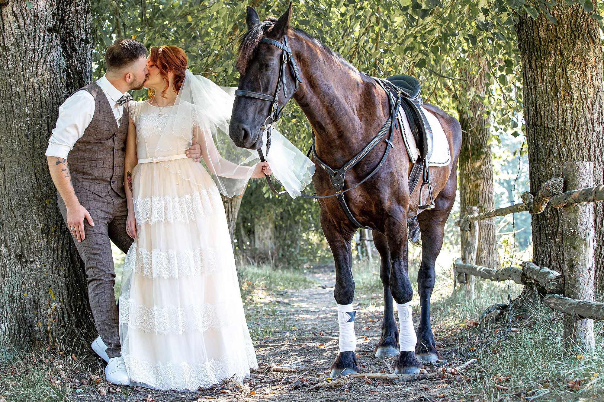 невеста держит под уздцы лошадь , другой рукой за руку жениха, целуются, снято по пояс.