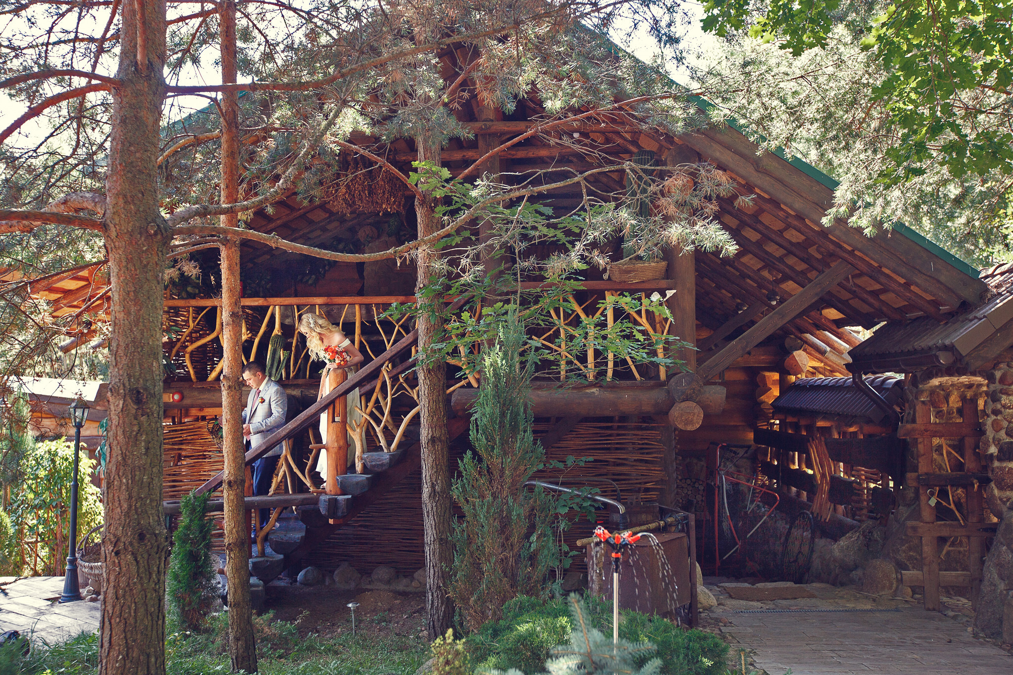 жених с невестой целуются на лестнице деревянного дома.