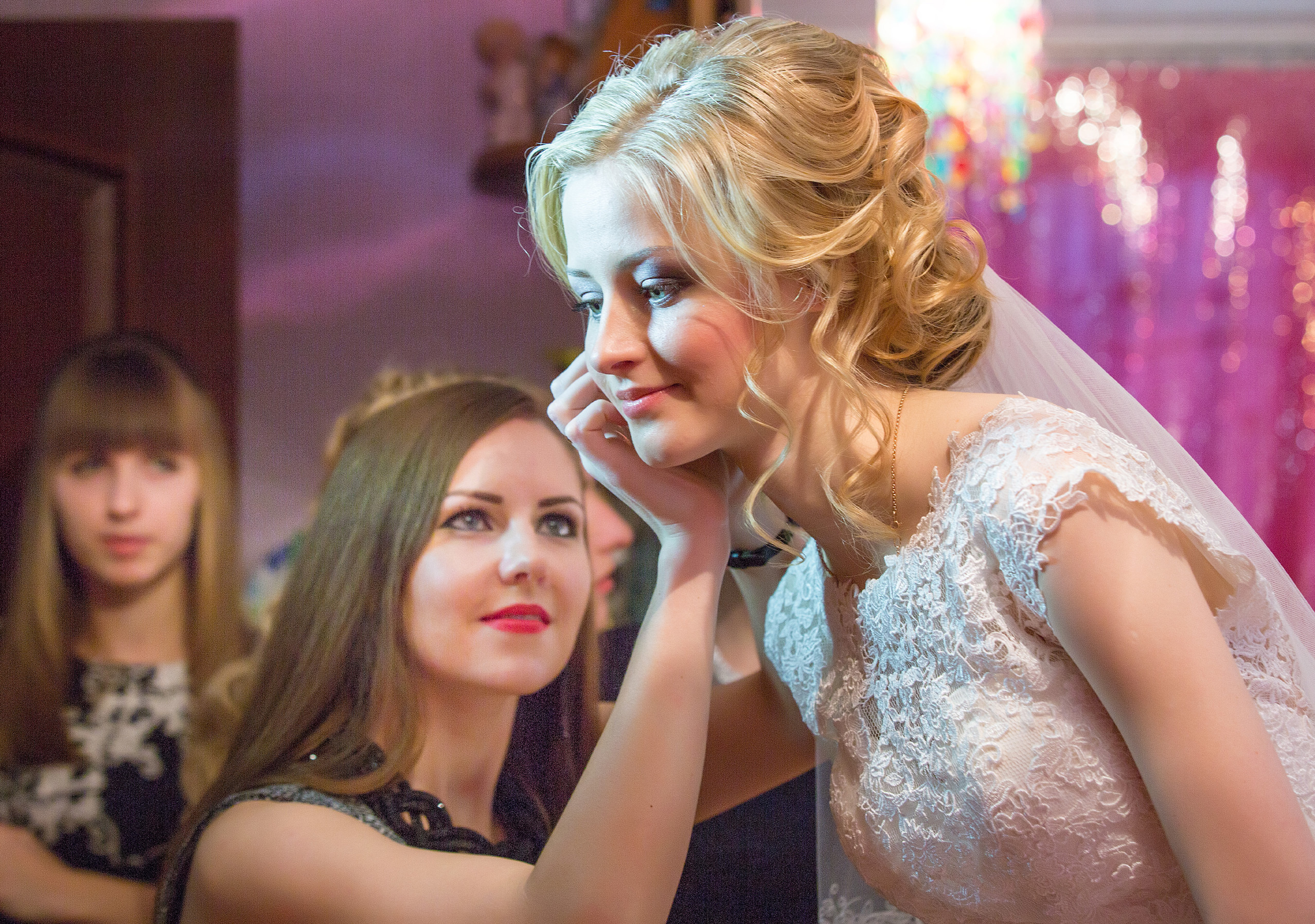 подружка помогает невесте одеть сережку.