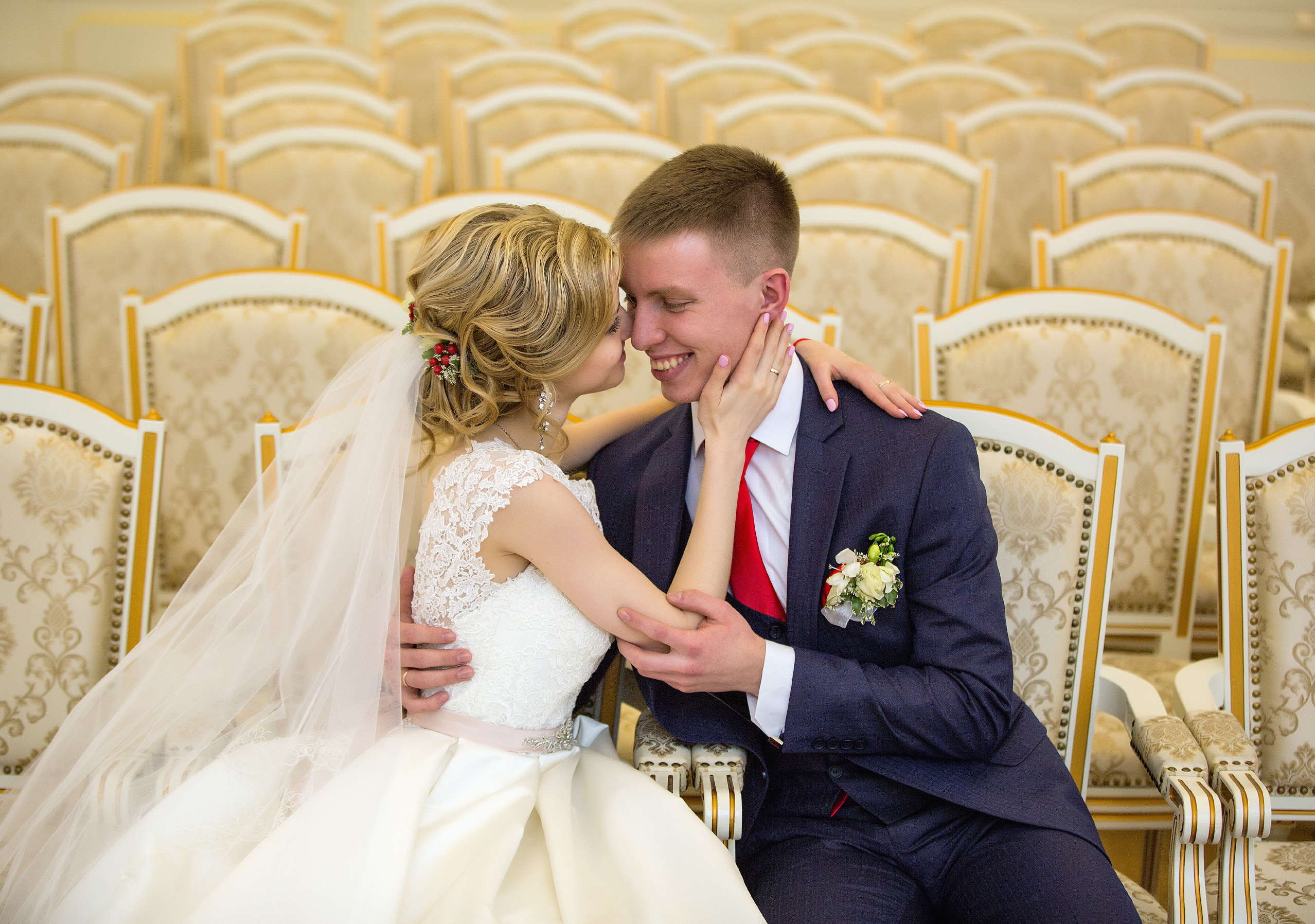 жених с невестой сидят в концертном зале на фоне желтых стульев.