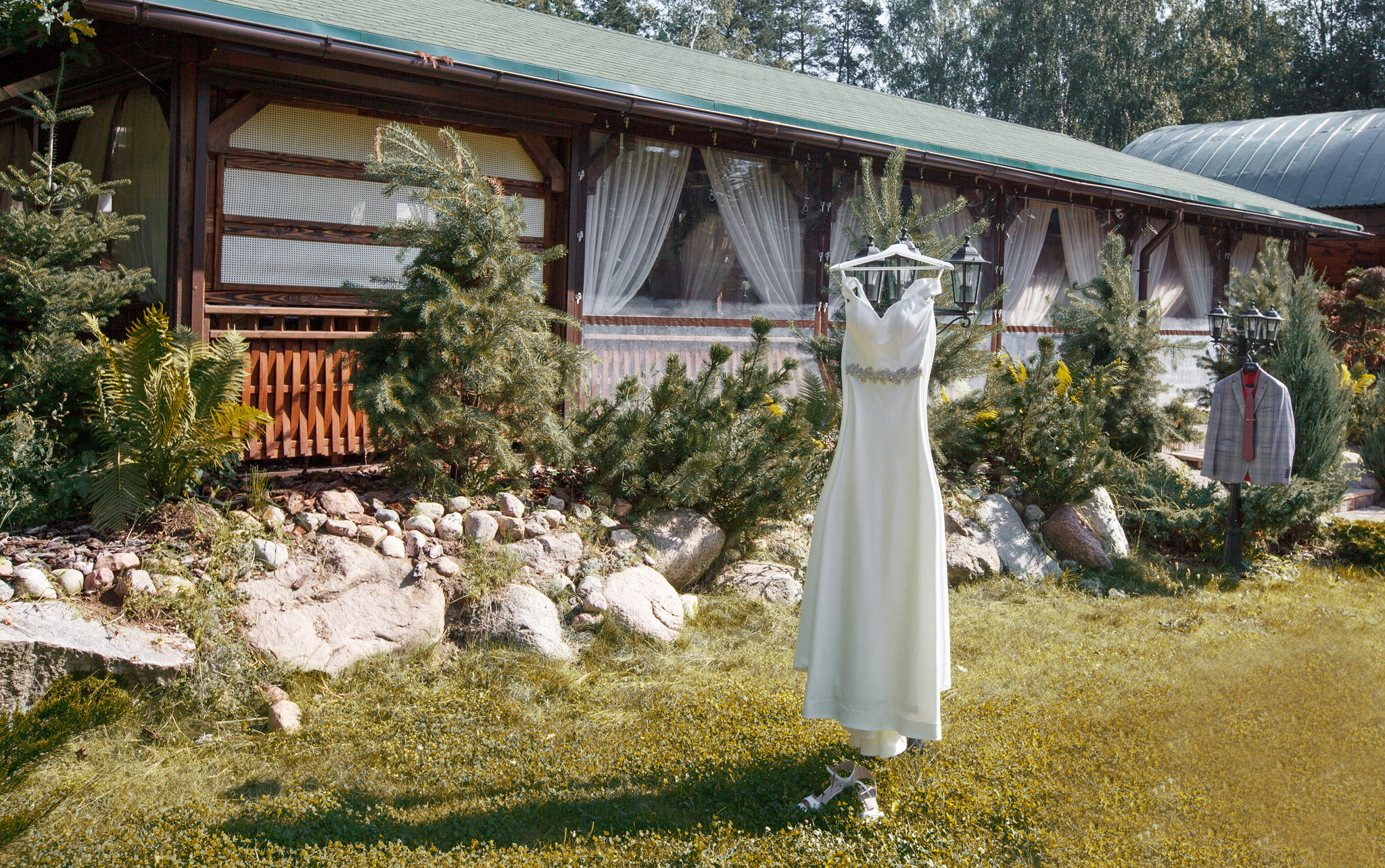 платье невесты на вешалке на фоне агроусадьбы.