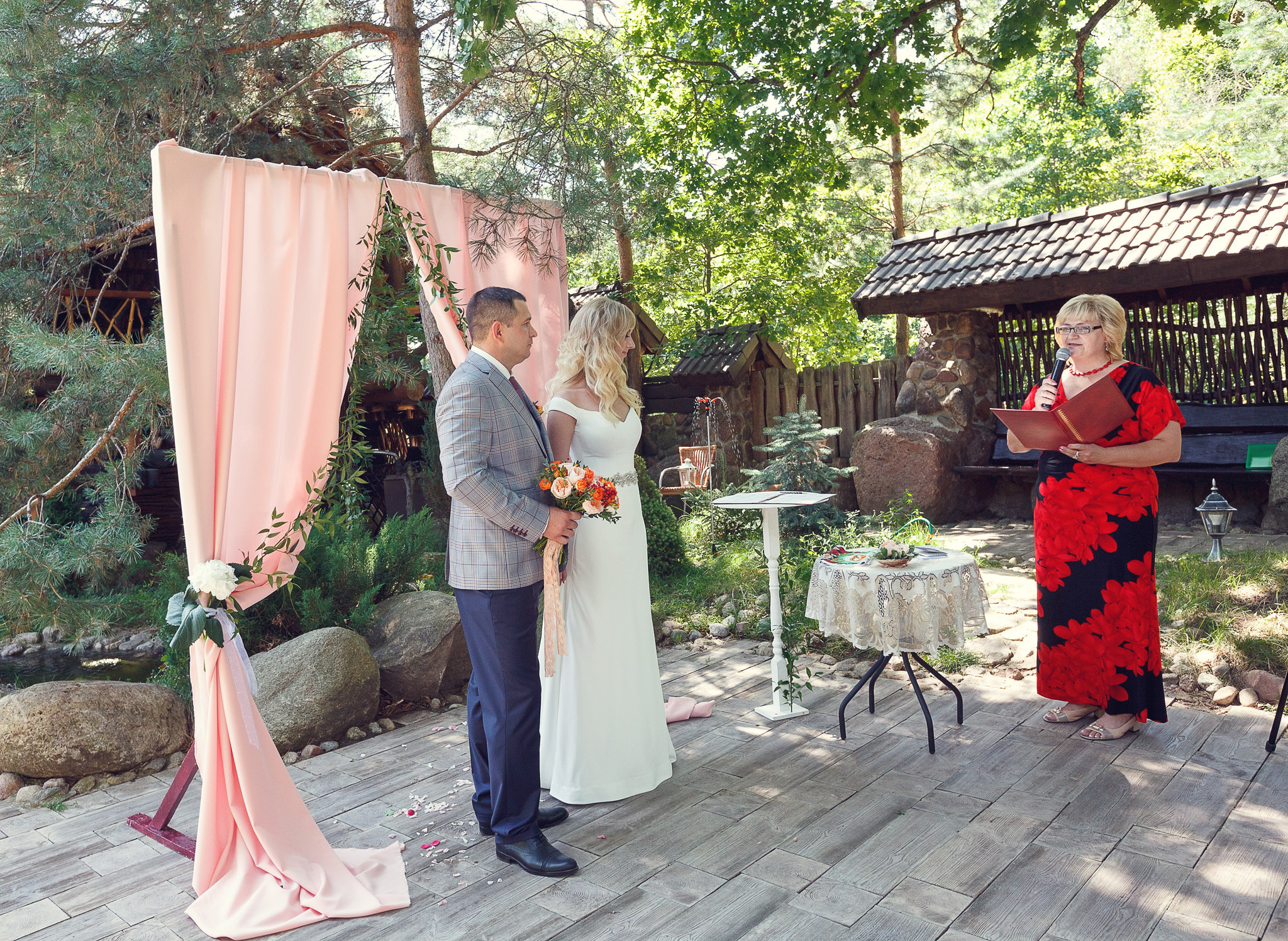 выездная регистрация, молодожены стоят друг с другом, смотрят на ведущую.