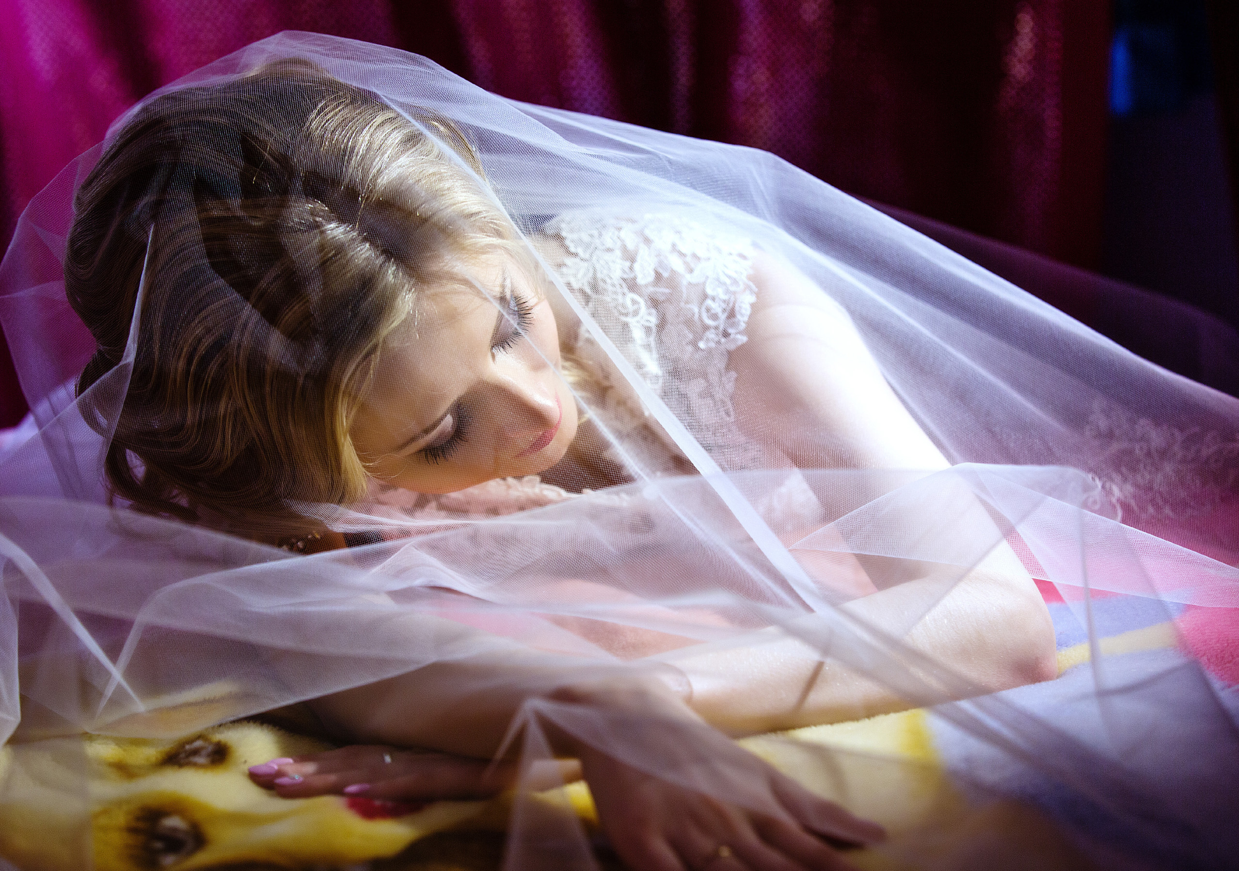 невеста лежит на кровати под фатой.