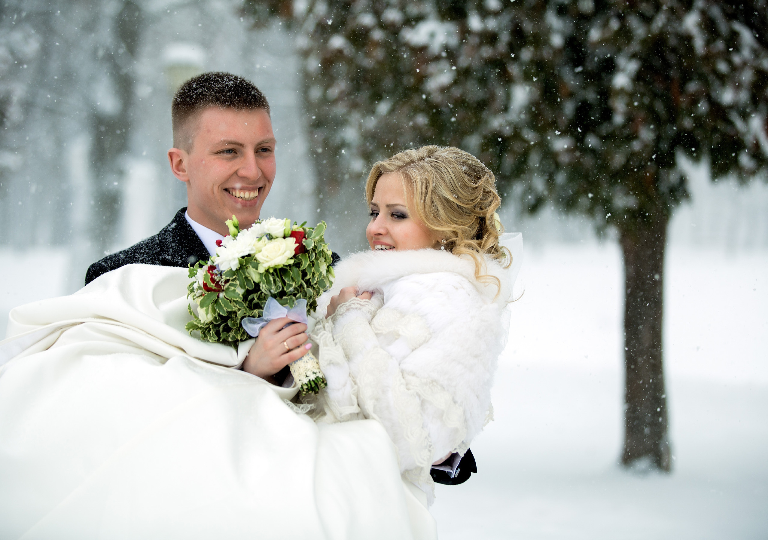 жених на руках несет невесту.