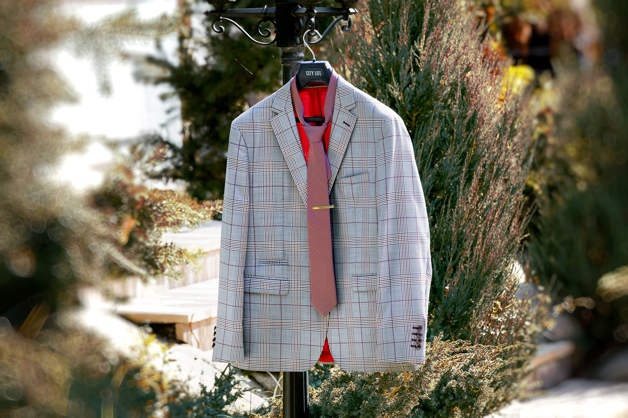 костюм жениха на вешалке на фоне природы.