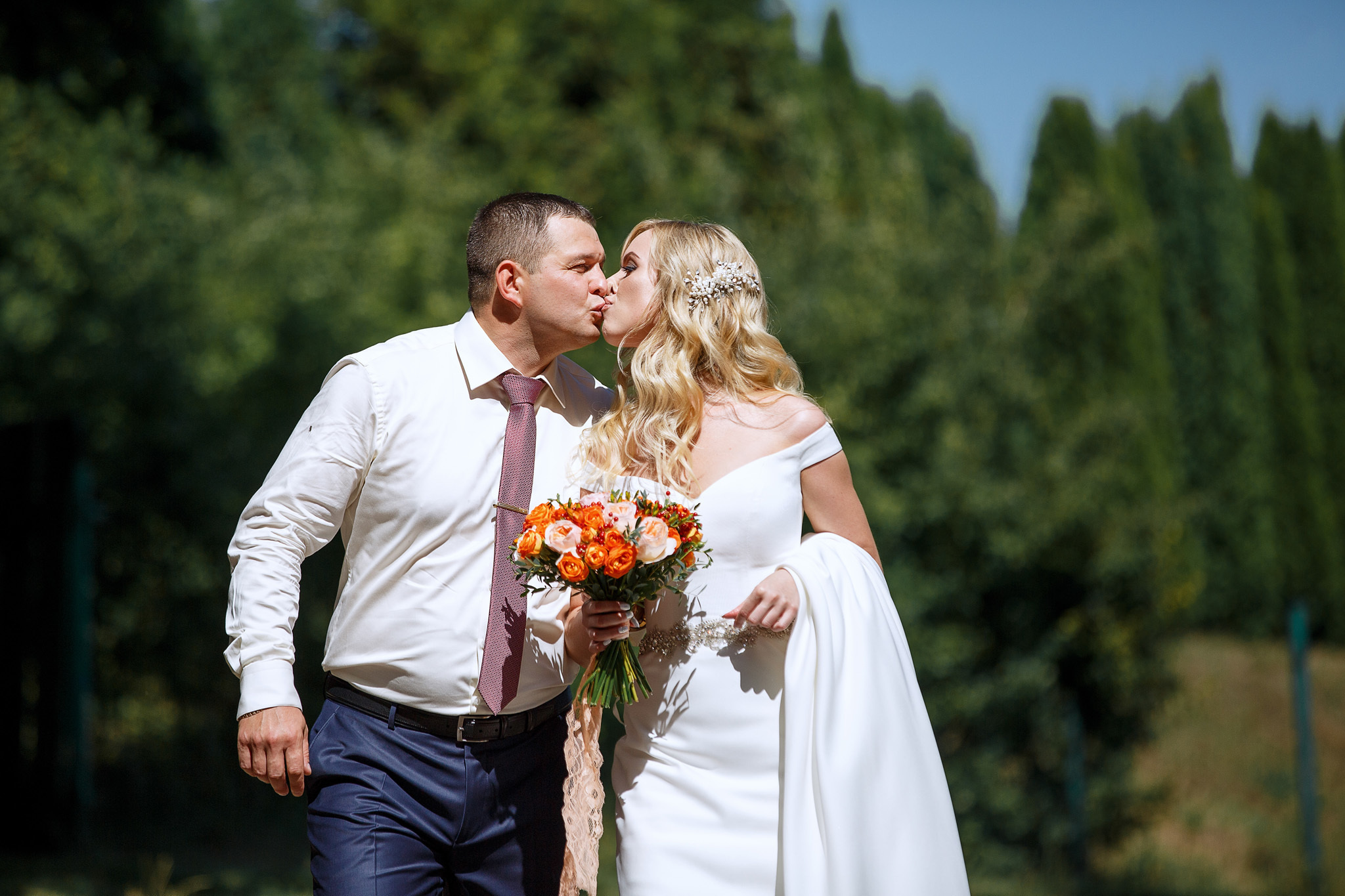 жених идет с невестой и целует ее.