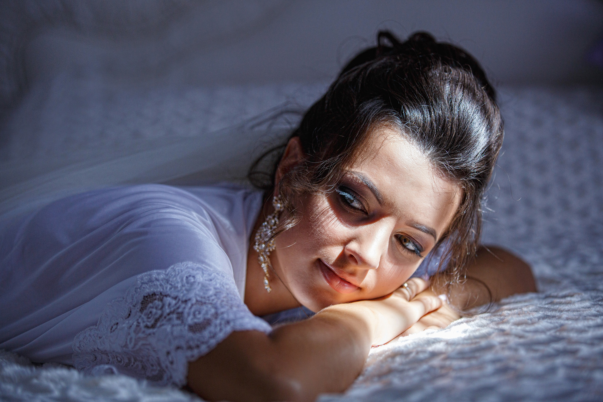 невеста в пеньюаре лежит на кровати.