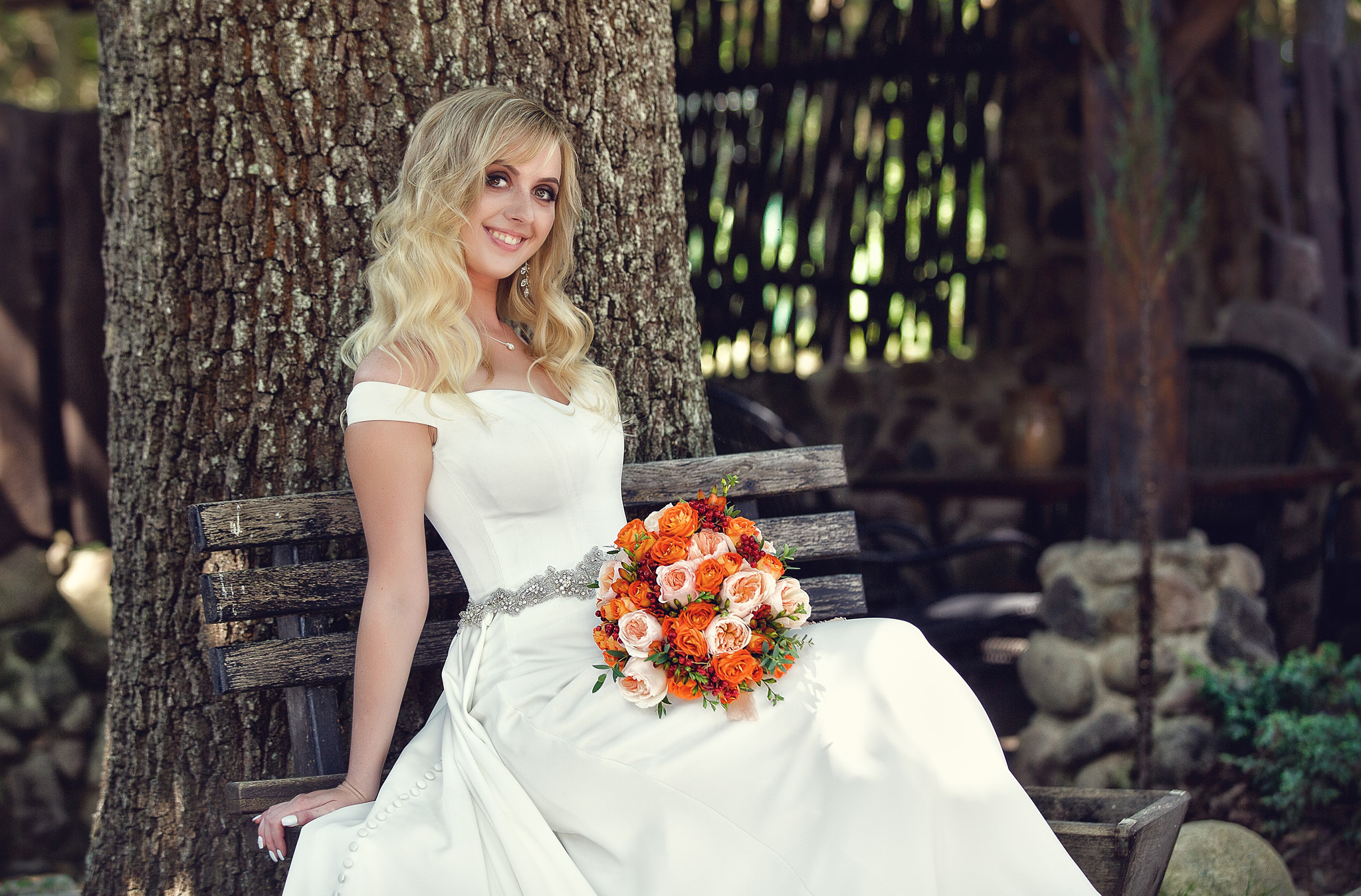 невеста с букетом сидит на скамейке.