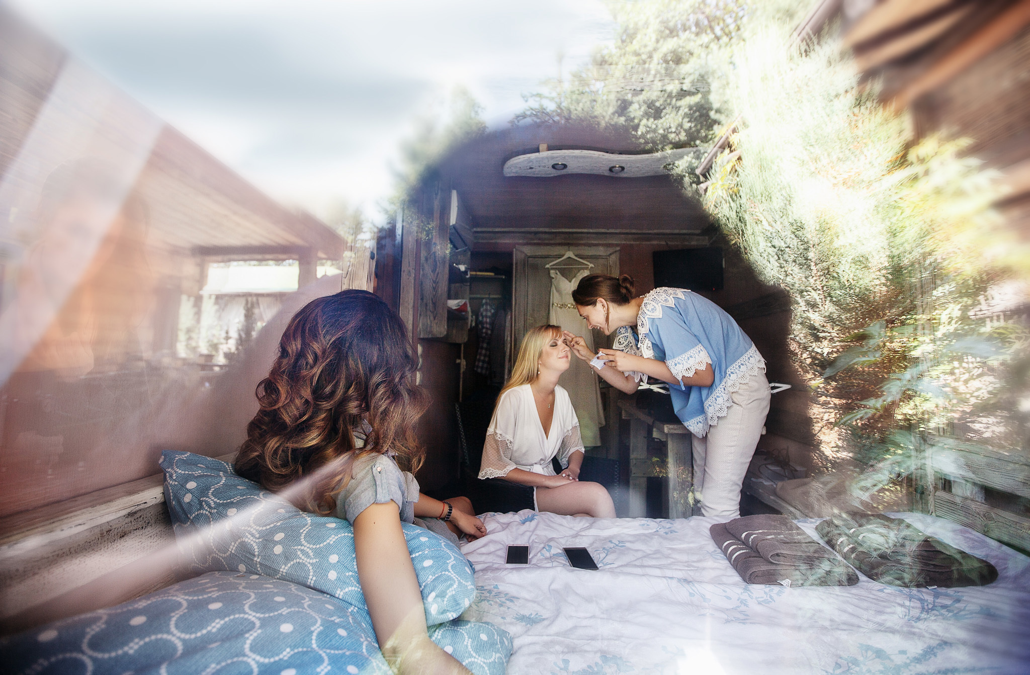 через окно в комнате невесты над ней работает визажист.