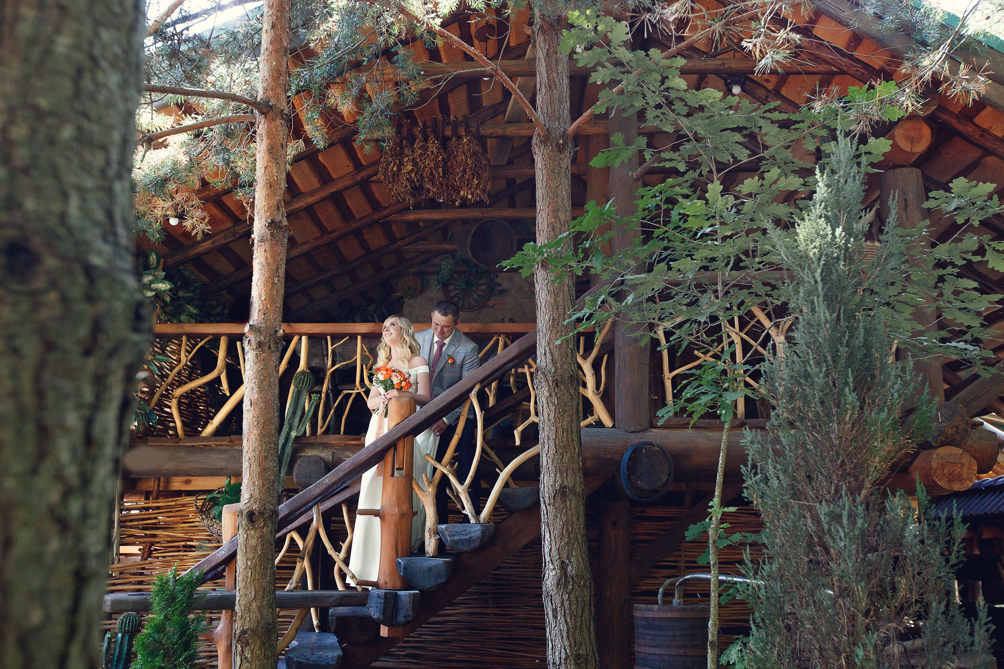 жених с невестой целуются на лестнице деревянного дома.