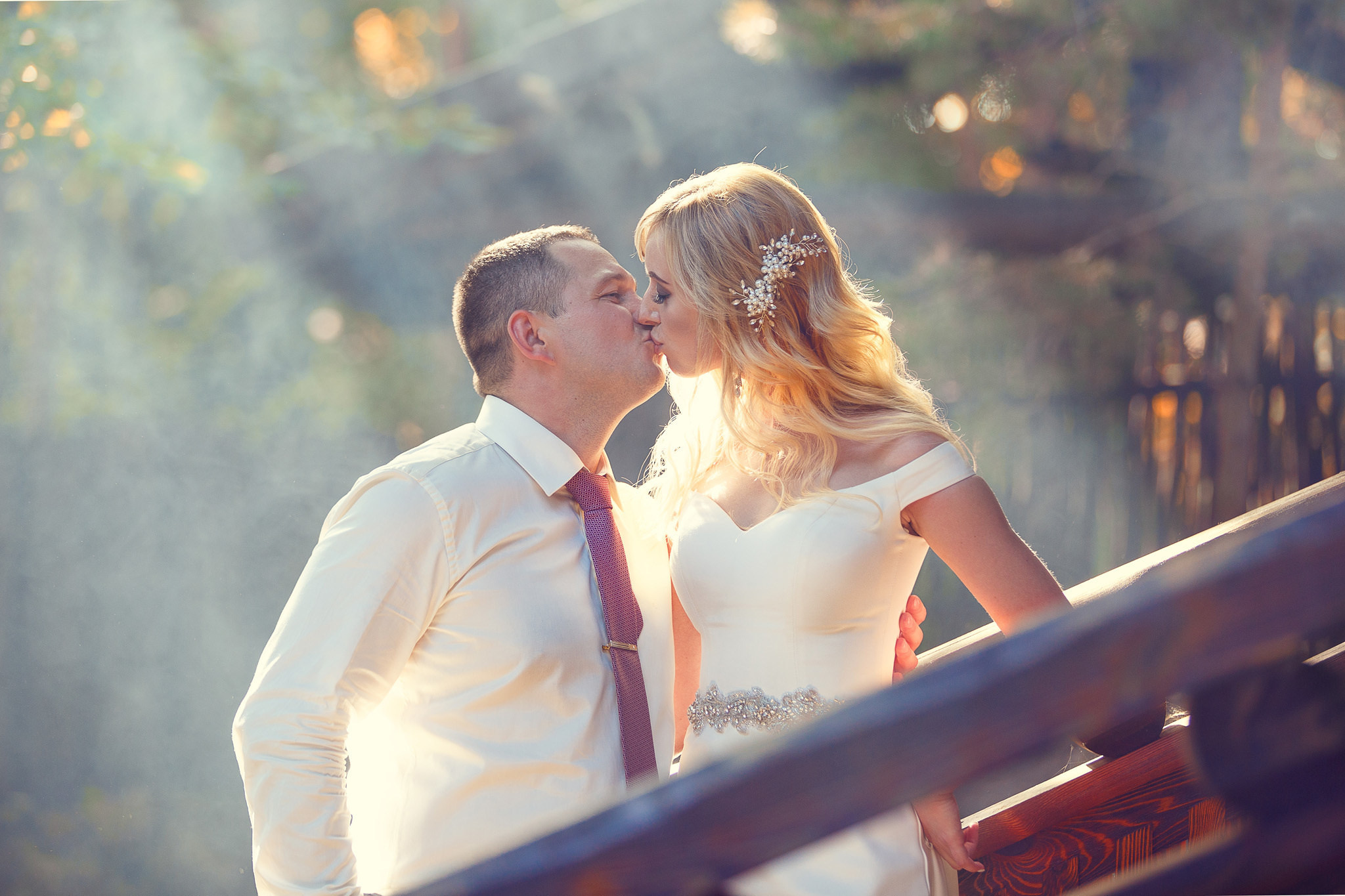 жених с невестой в лучах солнца целуются.