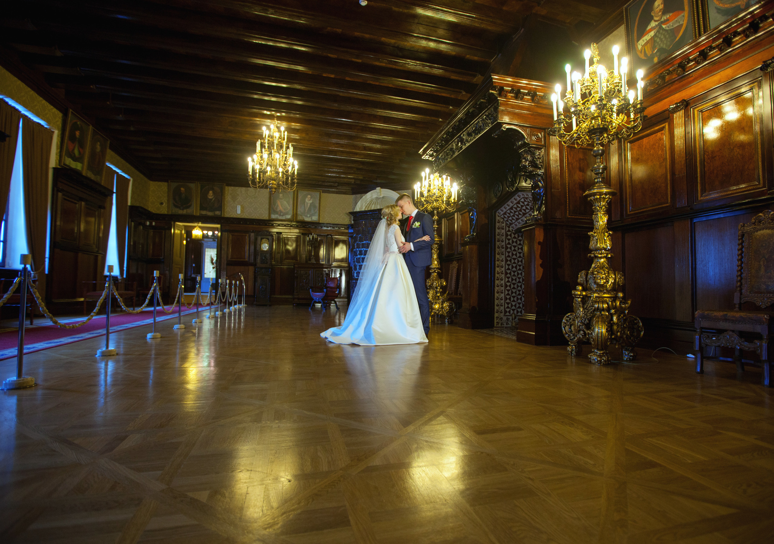 молодожены целуются в каминном зале замка.