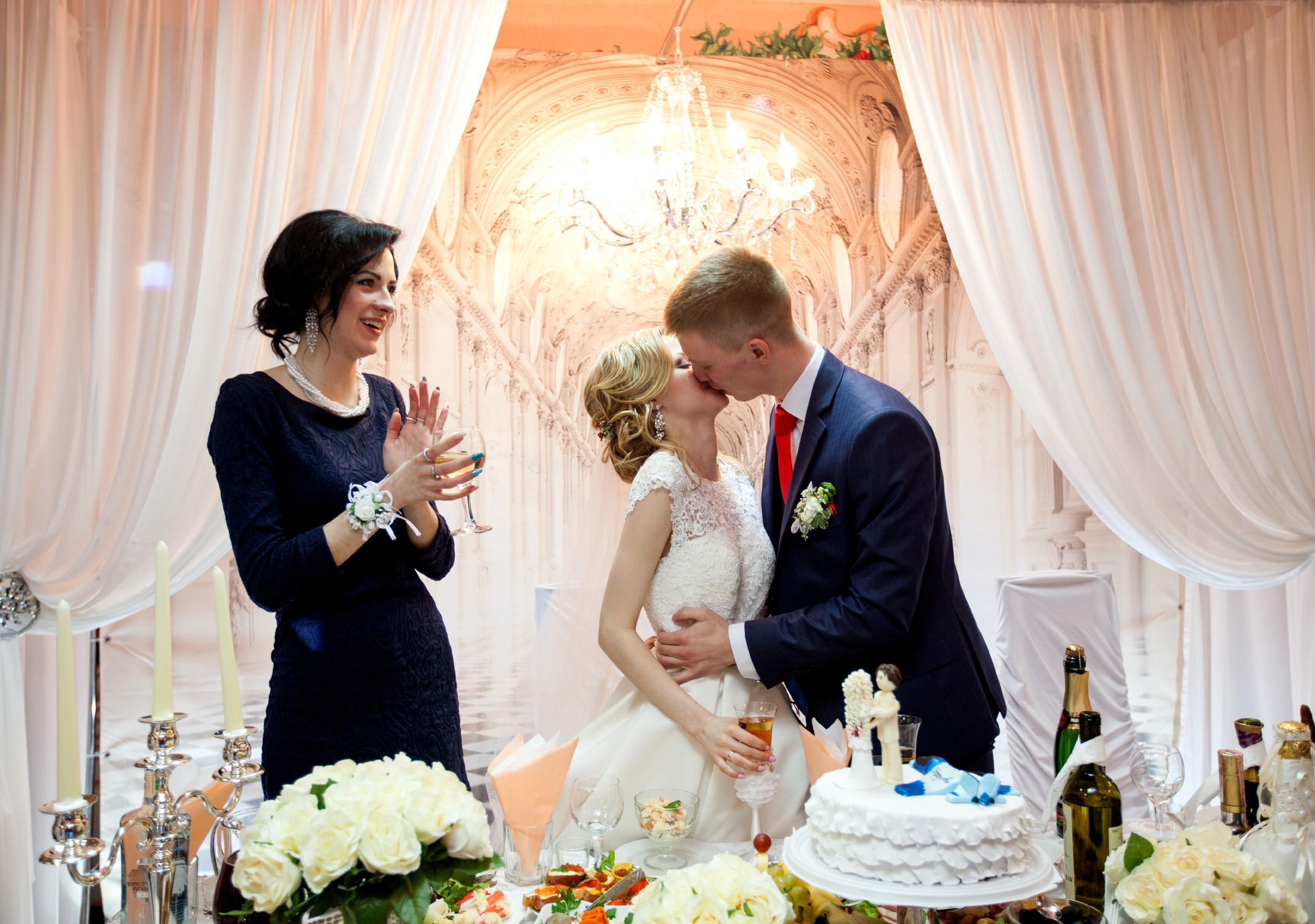 жених с невестой целуются, свидетельница смотрит на них.