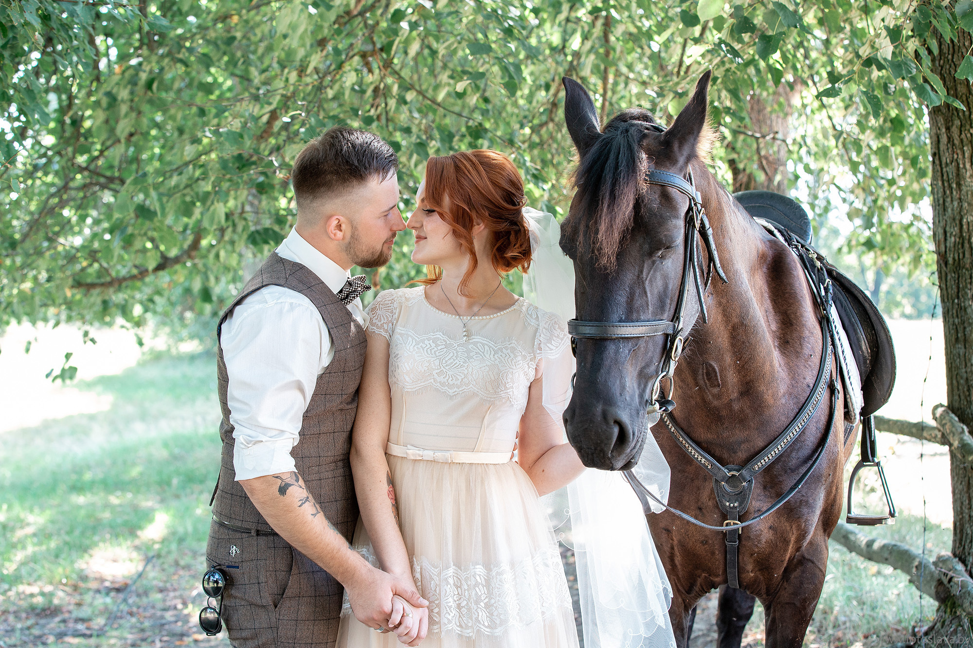невеста держит под уздцы лошадь , другой рукой за руку жениха, смотрят друг на друга влюбленно, снято по пояс.