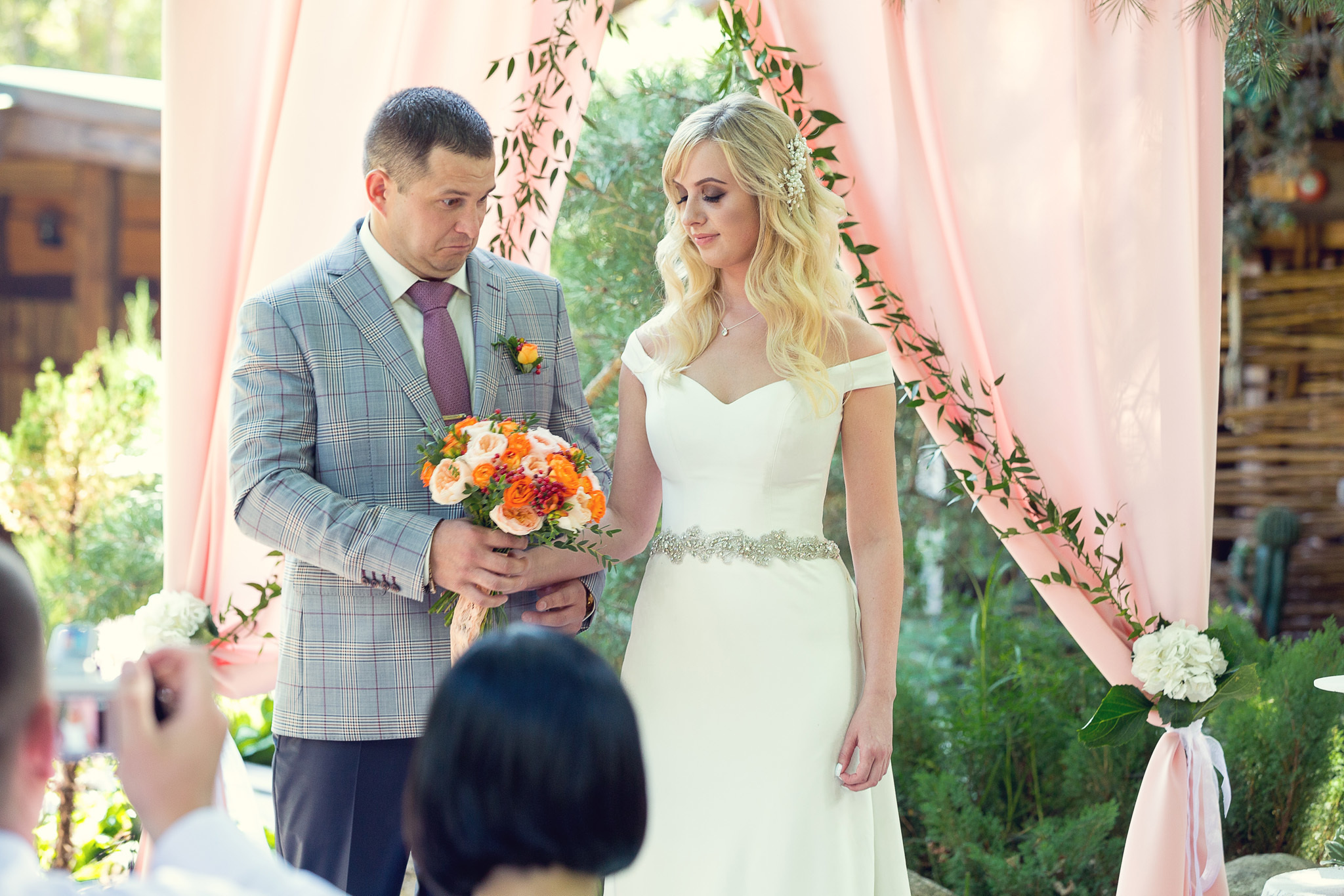 выездная регистрация, молодожены стоят рядом под аркой.